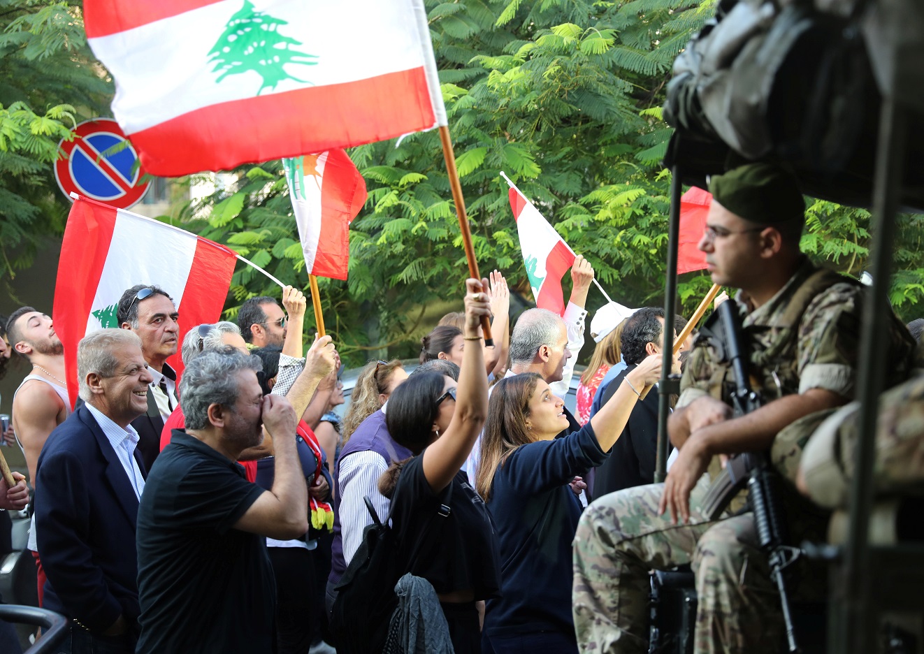 Demonstrators wave Lebanese flags as the pass by Lebanese soldiers during a protest in Beirut, Lebanon, October 31, 2019. REUTERS/Goran Tomasevic