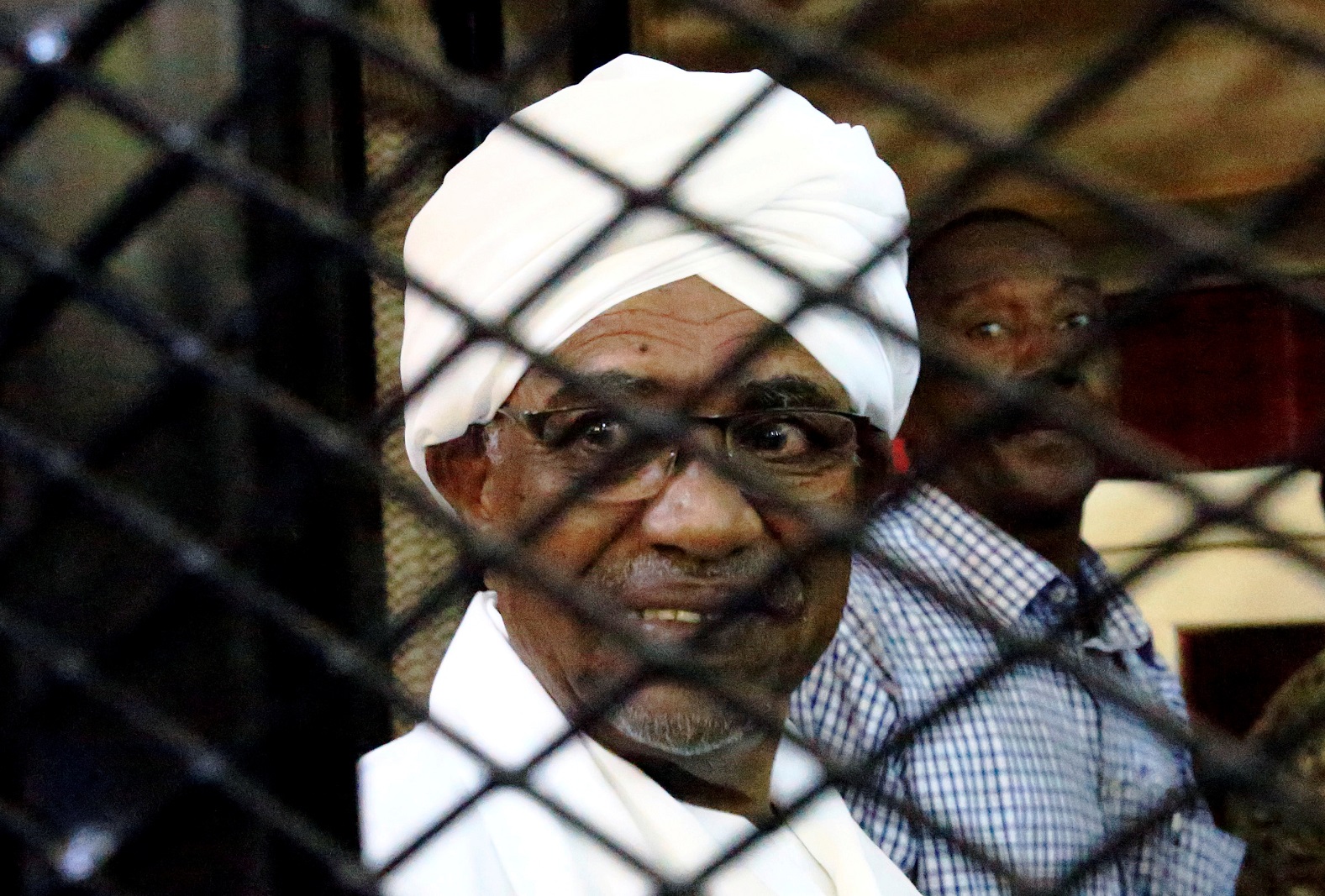 FILE PHOTO: Sudanese former president Omar Hassan al-Bashir smiles inside a cage as he faces corruption charges in a court in Khartoum, Sudan, August 31, 2019. REUTERS/Mohamed Nureldin Abdallah/File Photo