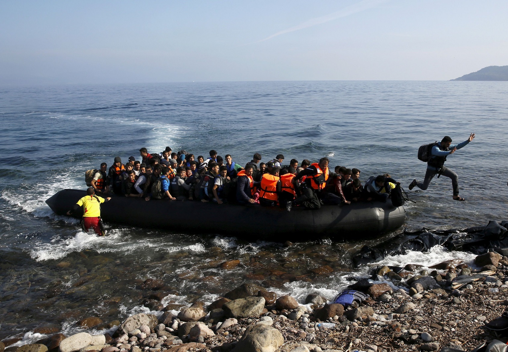 FILE PHOTO: An Afghan migrant jumps off an overcrowded raft onto a beach at the Greek island of Lesbos, October 19, 2015. REUTERS/Yannis Behrakis/File Photo