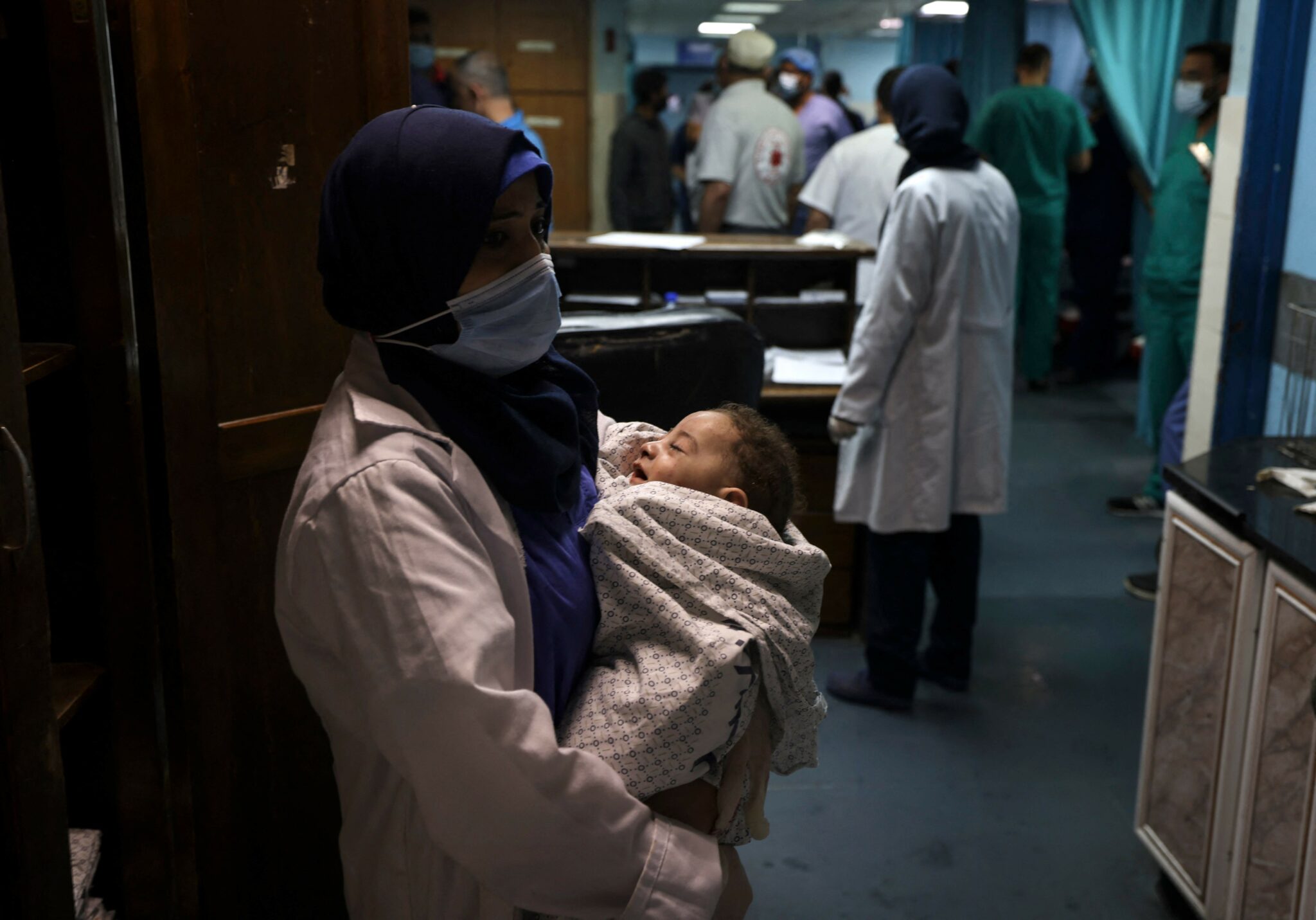 A nurse holds a baby, who was pulled alive from under the rubble while seven other family members perished, at Al-Shifa Hospital, after an Israeli air strike struck al-Shati Refugee Camp without advance warning during the night, in Gaza City early on May 15, 2021. Israel faced a widening conflict on May 14, as deadly violence erupted across the West Bank amid a massive aerial bombardment in Gaza and unprecedented unrest among Arabs and Jews inside the country. The West Bank clashes, described as among the most intense since the second intifada that began in 2000, left 11 people dead from Israeli fire, the Palestinian health ministry said, as overall fatalities from strikes on Gaza rose to 126. / AFP / MAHMUD HAMS