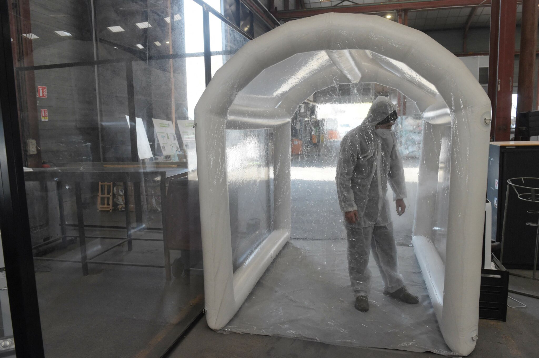 An employee sorting used masks, shows how he uses an inflatable tunnel with dry mist technology for desinfection at the Greenwishes waste sorting center in Gennevilliers, near Paris, on April 19, 2021. / AFP / Eric PIERMONT