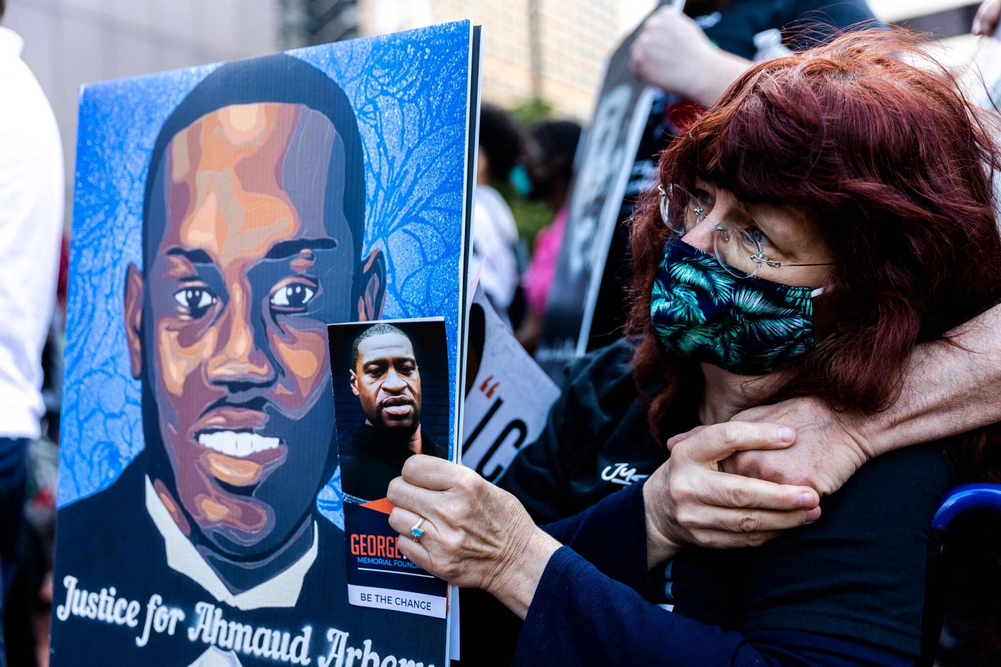 A woman holds portraits of Ahmaud Arbery and George Floyd during an event in remembrance of George Floyd in Minneapolis, Minnesota, on May 23, 2021. Supporters and relatives of African American George Floyd began gathering on May 23 ahead of the first anniversary of his death under a white policeman's knee, a killing that prompted a reckoning on racial injustice in the United States. / AFP / Kerem Yucel