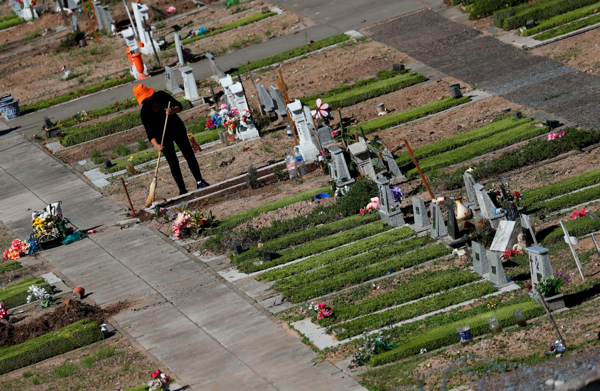 A woman sweeps the floor next to a grave at the Flores cemetery, amid the outbreak of the coronavirus disease (COVID-19) in Buenos Aires, Argentina April 21, 2021. REUTERS/Agustin Marcarian