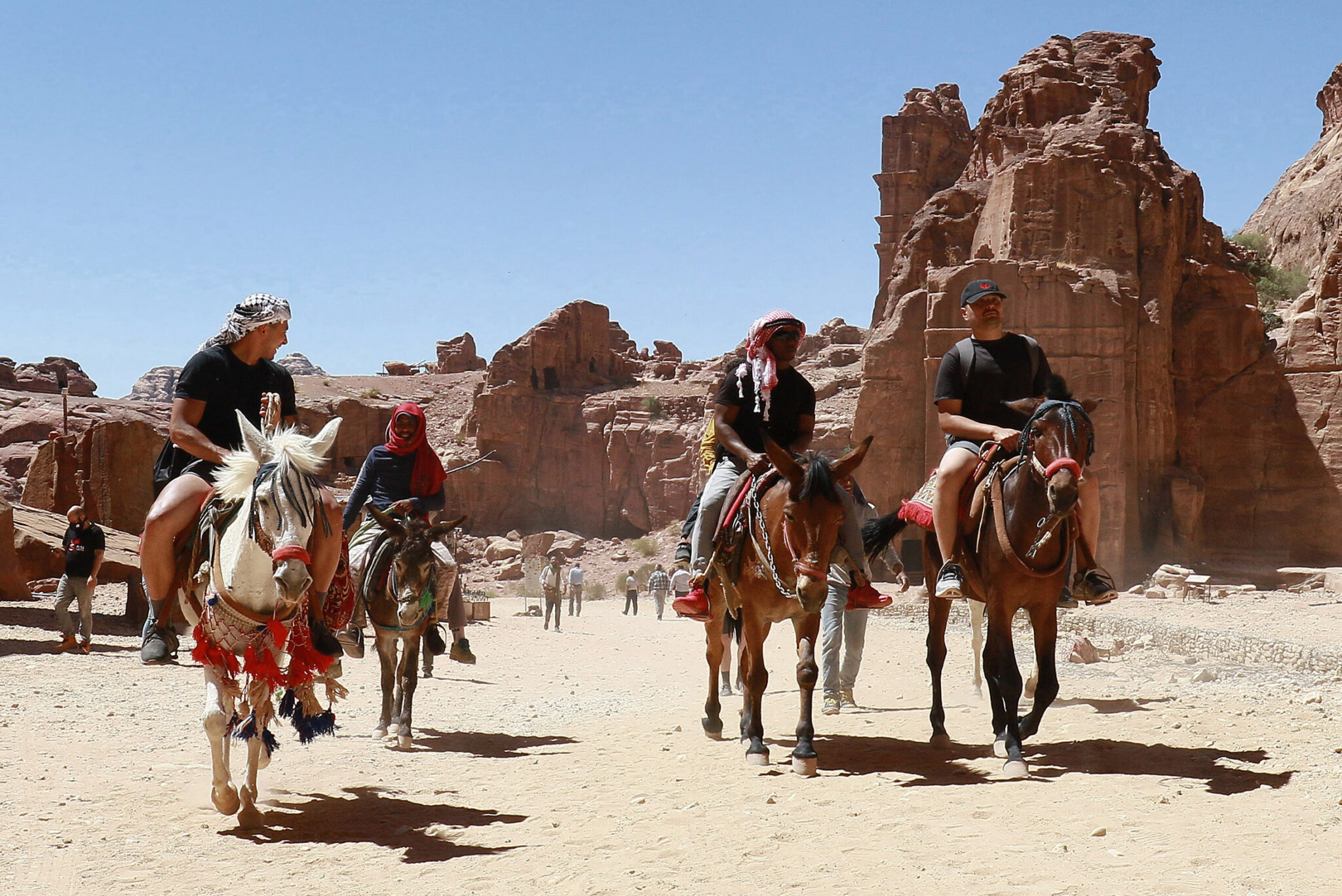 Tourists ride donkeys and horses as they visit Jordan's ancient city of Petra, on May 27, 2021, after it reopened following closure due to the Covid-19 coronavirus pandemic. Herds of hard-working donkeys once carried hordes of tourists on the rocky paths of Jordan's Petra, but visitor numbers crashed amid coronavirus and the loyal animals now face the chop. / AFP / Khalil MAZRAAWI