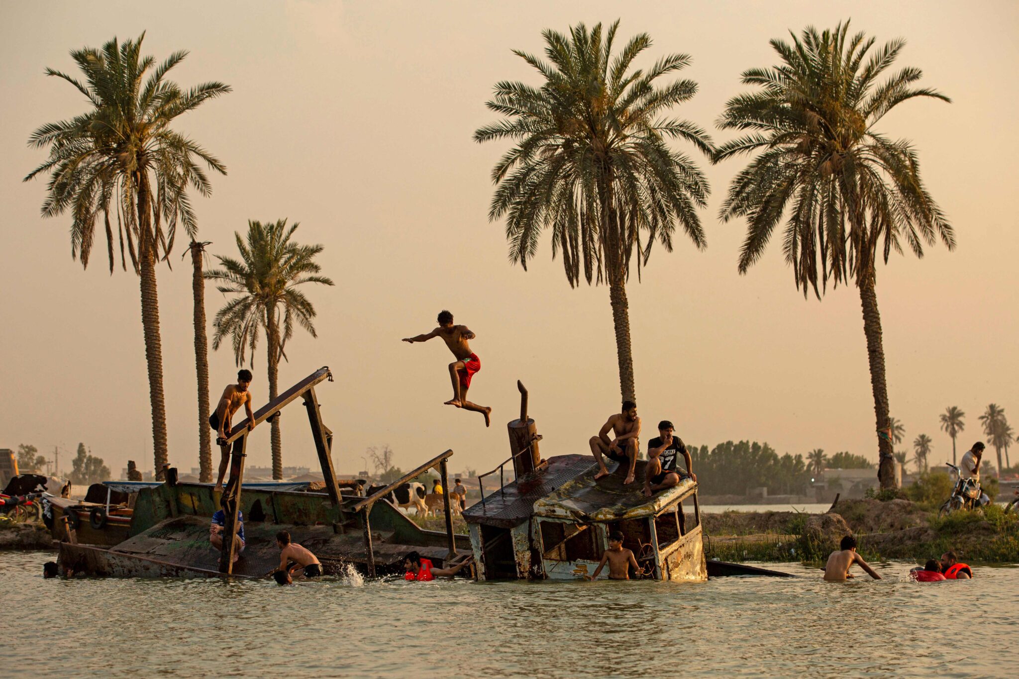 Iraqi youth swim in the Shatt Al-Arab river by the port of Maqil amid a heatwave in the southern Iraqi city of Basra on March 21, 2021 / AFP / Hussein FALEH