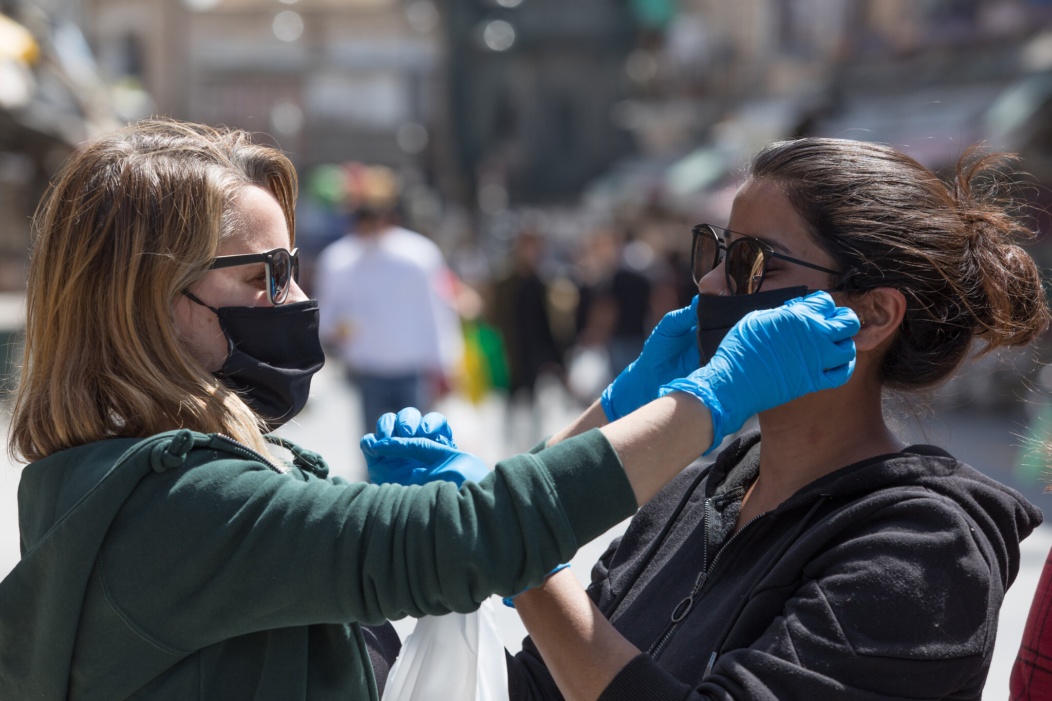 Women help each other to put on face masks at the Mahane Yehuda Market in Jerusalem on April 3, 2020. The government ordered on a partial lockdown, in order to prevent the spread of the Coronavirus. Photo by Nati Shohat/Flash90 *** Local Caption *** סופר
מרקת
קורונה
קניות
רחובות יהודה