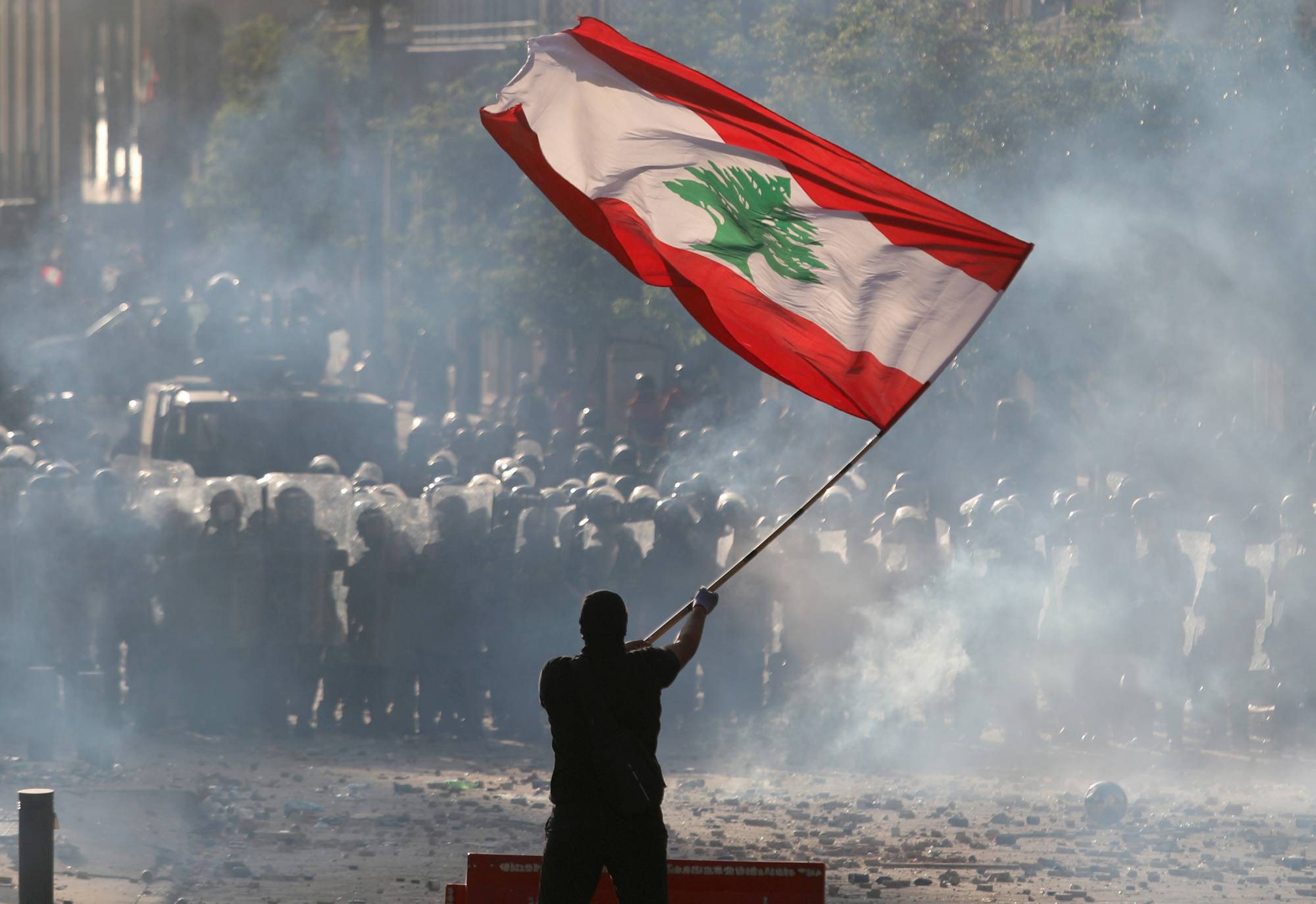 A demonstrator waves the Lebanese flag in front of riot police during a protest in Beirut, Lebanon, August 8, 2020. REUTERS/Goran Tomasevic TPX IMAGES OF THE DAY