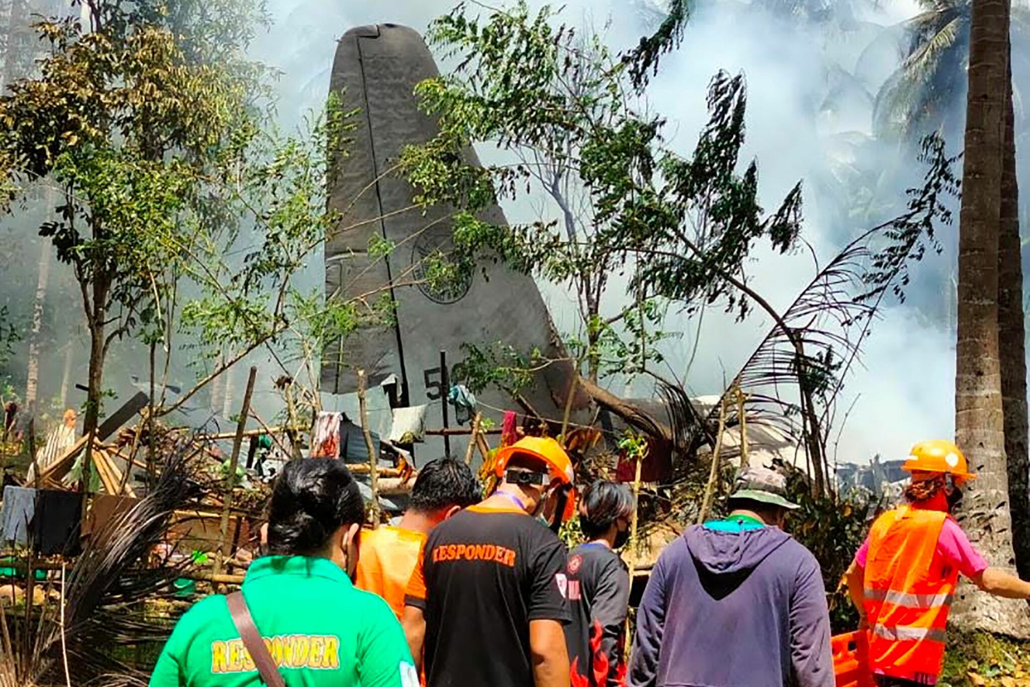 TOPSHOT - In this handout photo taken on July 4, 2021 and received from the Philippine military Joint Task Force-Sulu (JTF-Sulu), rescue workers arrive as smoke billows from the wreckage of a Philippine Airforce C-130 transport plane after it crashed near the airport in Jolo town, Sulu province on the southern island of Mindanao. -----EDITORS NOTE --- RESTRICTED TO EDITORIAL USE - MANDATORY CREDIT "AFP PHOTO / JOINT TASK FORCE-SULU (JTF-SULU) " - NO MARKETING - NO ADVERTISING CAMPAIGNS - DISTRIBUTED AS A SERVICE TO CLIENTS / AFP / Joint Task Force-Sulu / Handout / -----EDITORS NOTE --- RESTRICTED TO EDITORIAL USE - MANDATORY CREDIT "AFP PHOTO / JOINT TASK FORCE-SULU (JTF-SULU) " - NO MARKETING - NO ADVERTISING CAMPAIGNS - DISTRIBUTED AS A SERVICE TO CLIENTS