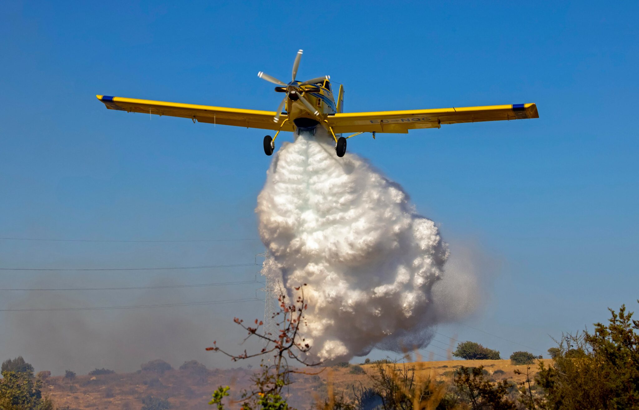 A Spanish Air Tractor firefighting planne dumps water on the southern slopes of the Troodos mountains close to Agioi Vavatsinias village as a major fire continues to burn on the Mediterranean island of Cyprus on July 4, 2021. A huge forest blaze in Cyprus killed four people, destroyed homes and forced evacuations of villages, police said Sunday, as Greece, Israel and other countries deployed fire-fighting planes to the Mediterranean island. / AFP / Georgio PAPAPETROU