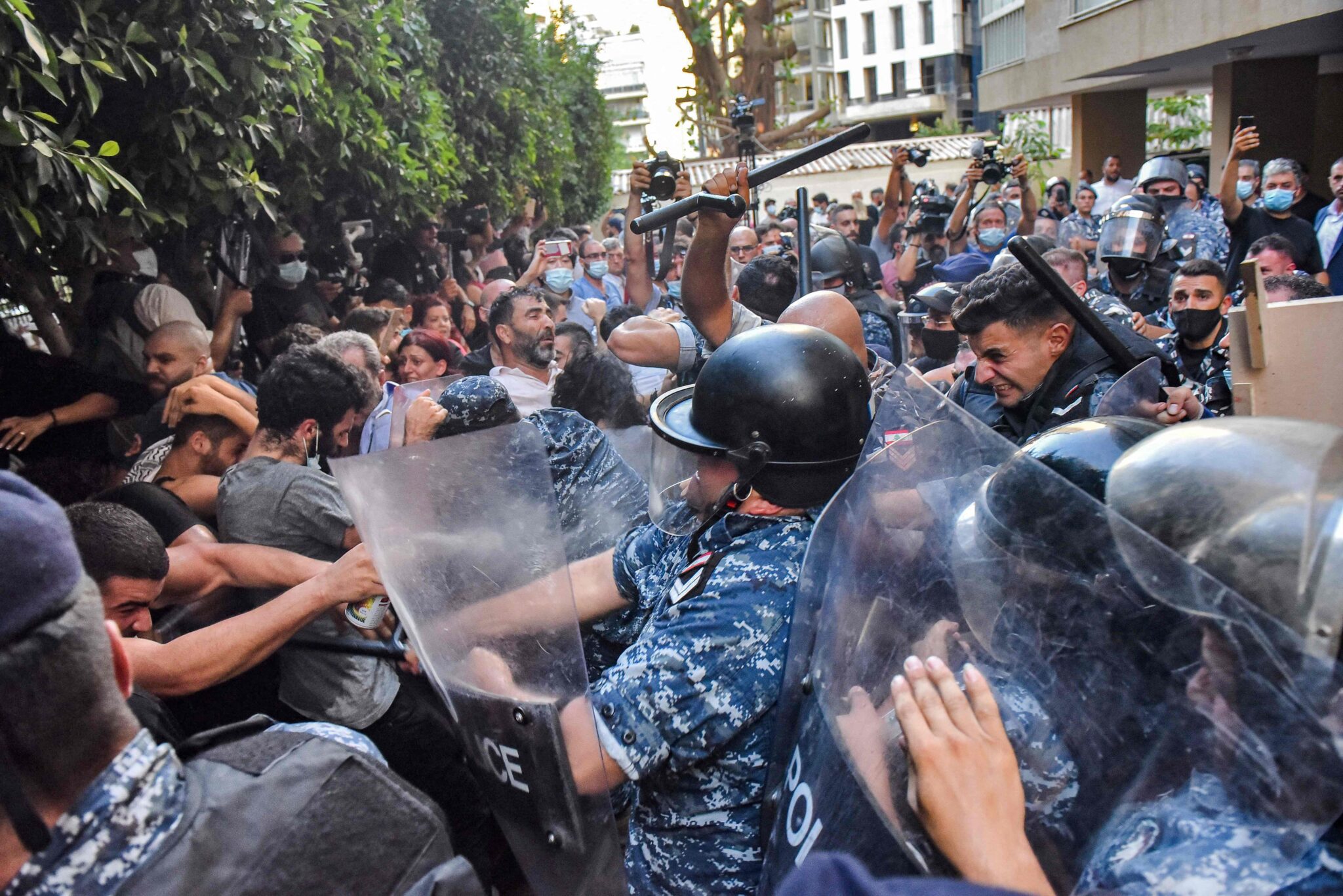 TOPSHOT - Protesters scuffle with security forces as they attempt to break into the residence of Lebanon's Interior Minister in the Qoraitem neighbourhood of western Beirut on July 13, 2021, following a demonstration by the families of the Beirut blast victims. Lebanese police fired tear gas during scuffles with demonstrators outside the home of caretaker interior minister Mohammad Fahmi who protesters accuse of stalling a probe into last summer's port blast. The protests called for by relatives of the victims of the August 4 explosion swelled by the evening, with dozens of demonstrators streaming in to help families storm Fahmi's heavily guarded Beirut home. / AFP / -