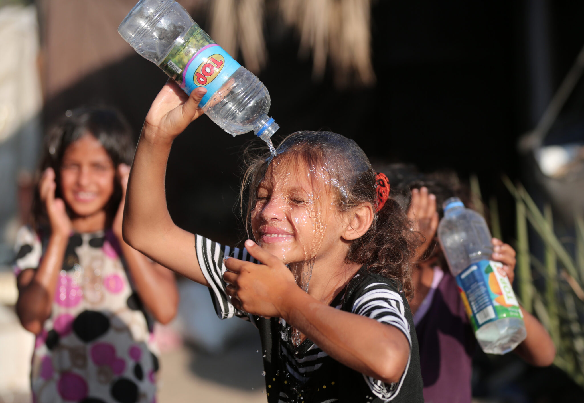 (210629) -- GAZA, June 29, 2021 (Xinhua) -- A Palestinian girl pours water to cool off during hot weather near Khan Younis refugee camp in southern Gaza Strip, on June 29, 2021. (Photo by Yasser Qudih/Xinhua)