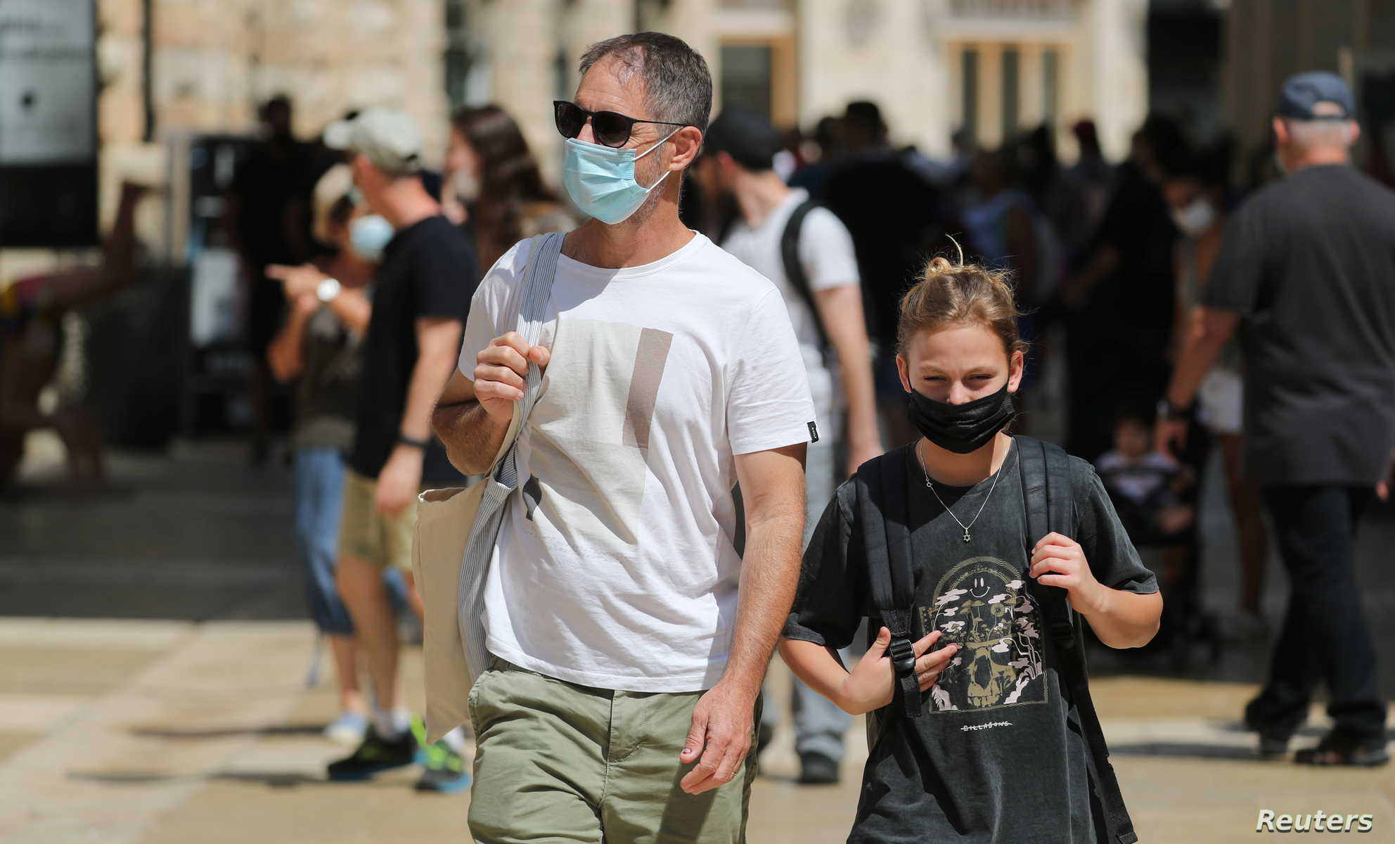 People wearing face masks to help fight the spread of the coronavirus disease (COVID-19) walk past shops in a market in Jerusalems August 11,2021.REUTERS/Ammar Awad