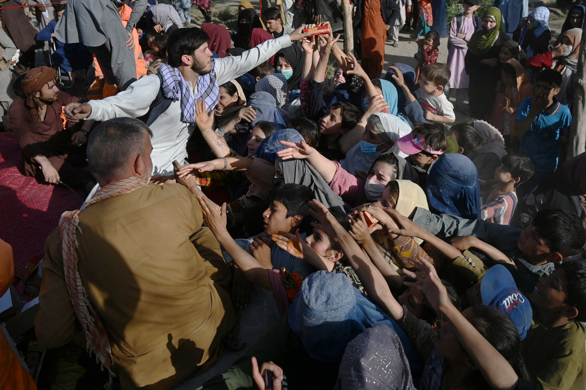 TOPSHOT - Internally displaced Afghan families fled from Kunduz and Takhar province due to battles between Taliban and Afghan security forces, collect food in Kabul on Agust 9, 2021. (Photo by Wakil KOHSAR / AFP)