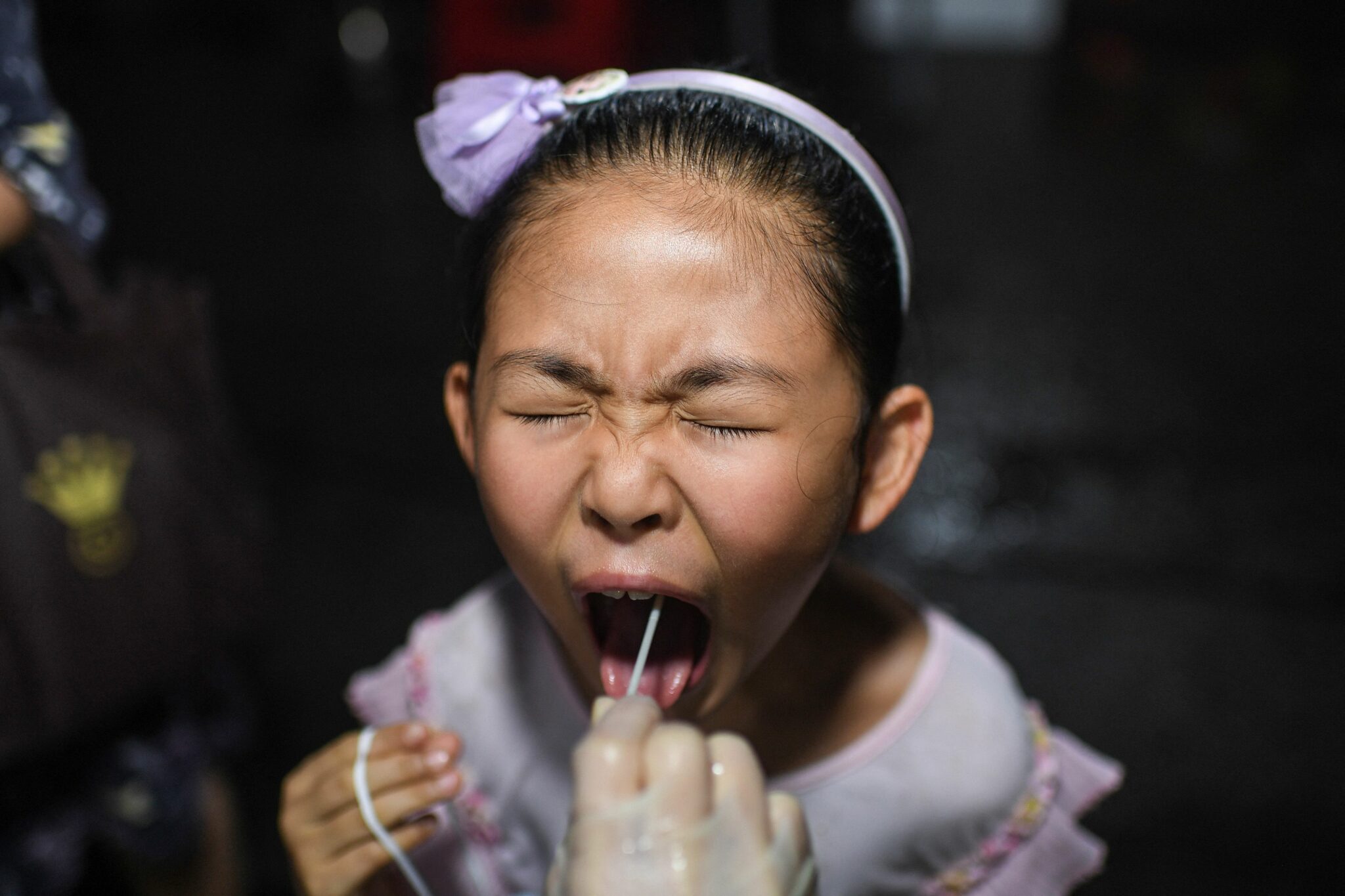 TOPSHOT - This photo taken on August 11, 2021 shows a child receiving a nucleic acid test for the Covid-19 coronavirus at a residental area in Wuhan, in China's central Hubei province. China OUT (Photo by AFP)