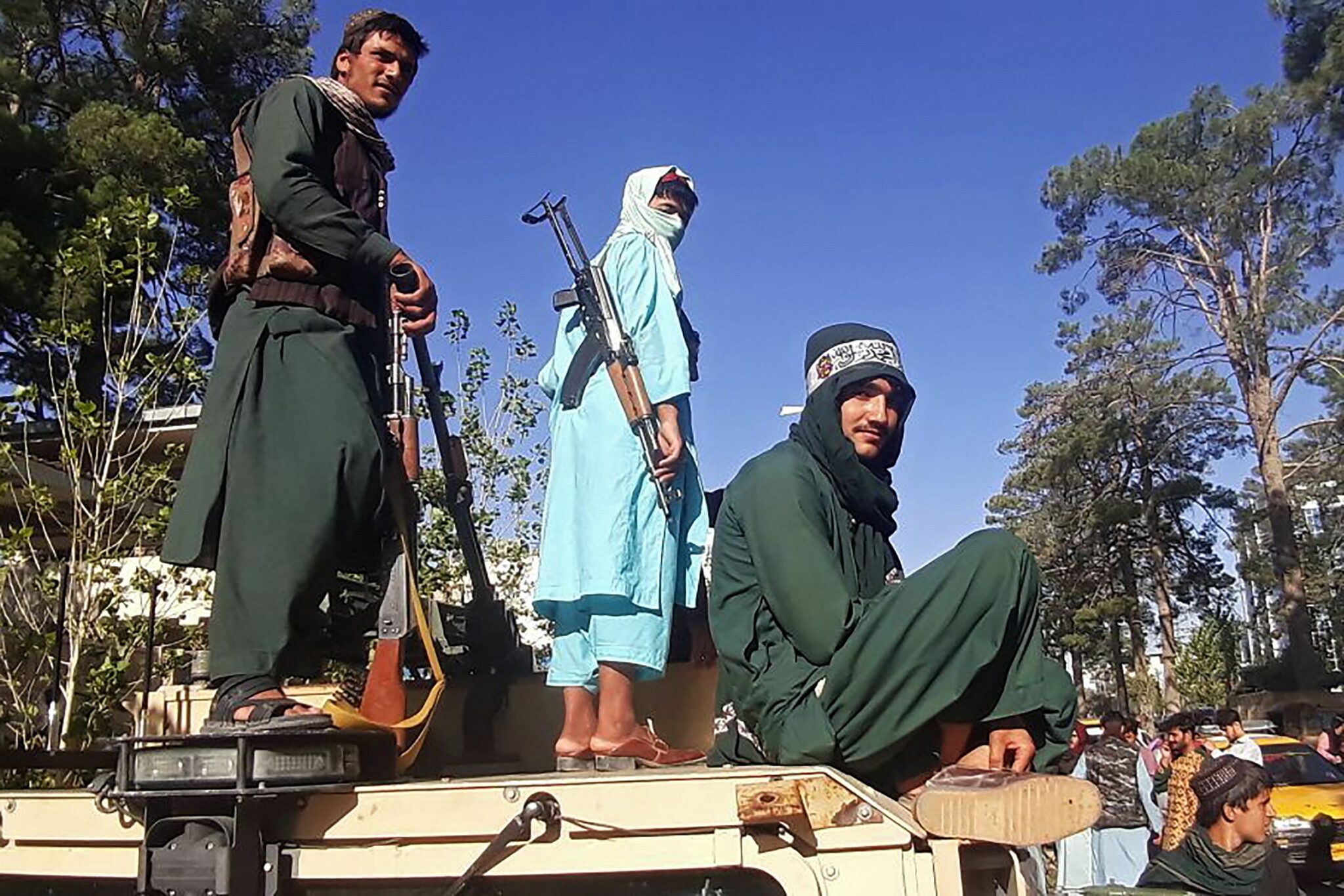 In this picture taken on August 13, 2021, Taliban fighters stand on a vehicle along the roadside in Herat, Afghanistan's third biggest city, after government forces pulled out the day before following weeks of being under siege. (Photo by AFP)