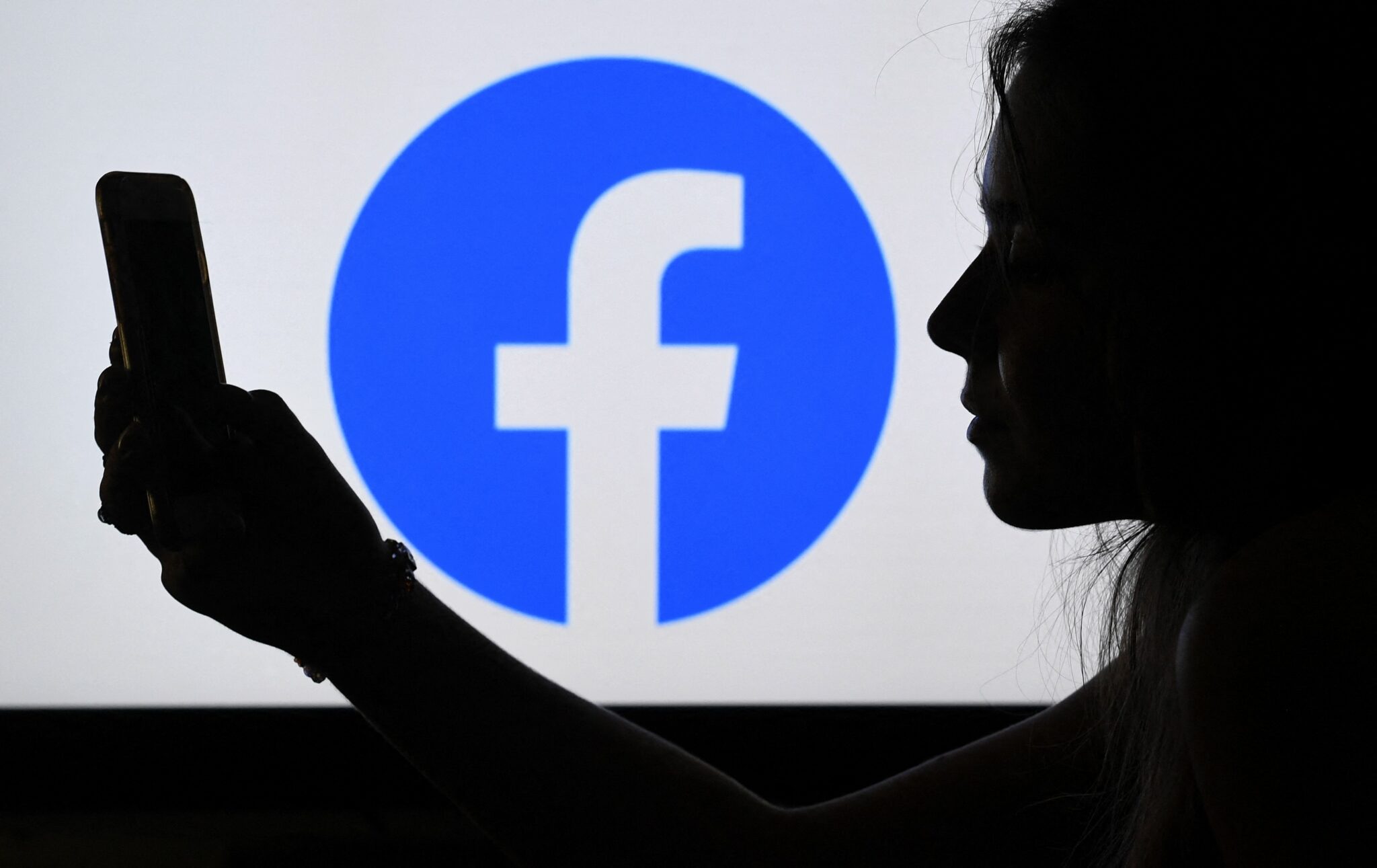 (FILES) In this file photo illustration, a person looks at a smart phone with a Facebook App logo displayed on the background, on August 17, 2021, in Arlington, Virginia. Facebook said on August 18, 2021 vaccine "hesitancy" is declining in the United States and other countries, and credits its efforts to filter out misinformation and promote authoritative information for helping the trend.
In releasing its quarterly transparency report, Facebook said the latest data showed vaccine hesitancy is down by 50 percent among US users of the social network, with significant declines in other countries. (Photo by OLIVIER DOULIERY / AFP)