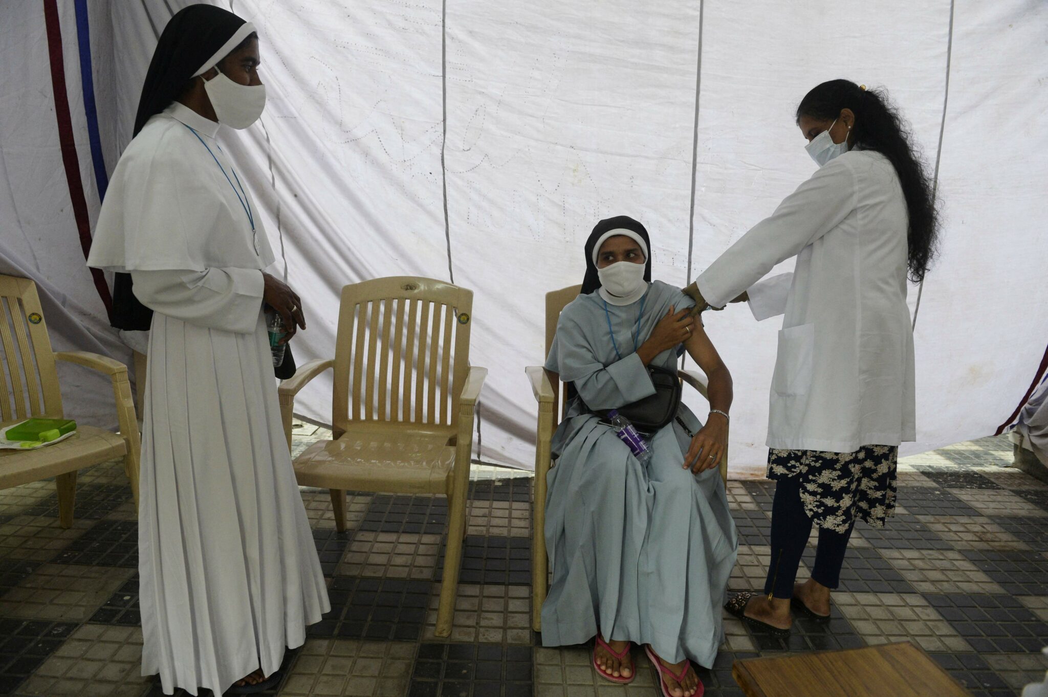 A health worker inoculates a catholic nun with the first dose of the Covishield vaccine against the Covid-19 coronavirus during a vaccination drive at Saint Mary's Basilica in Secunderabad, the twin city of Hyderabad on August 19, 2021. (Photo by NOAH SEELAM / AFP)