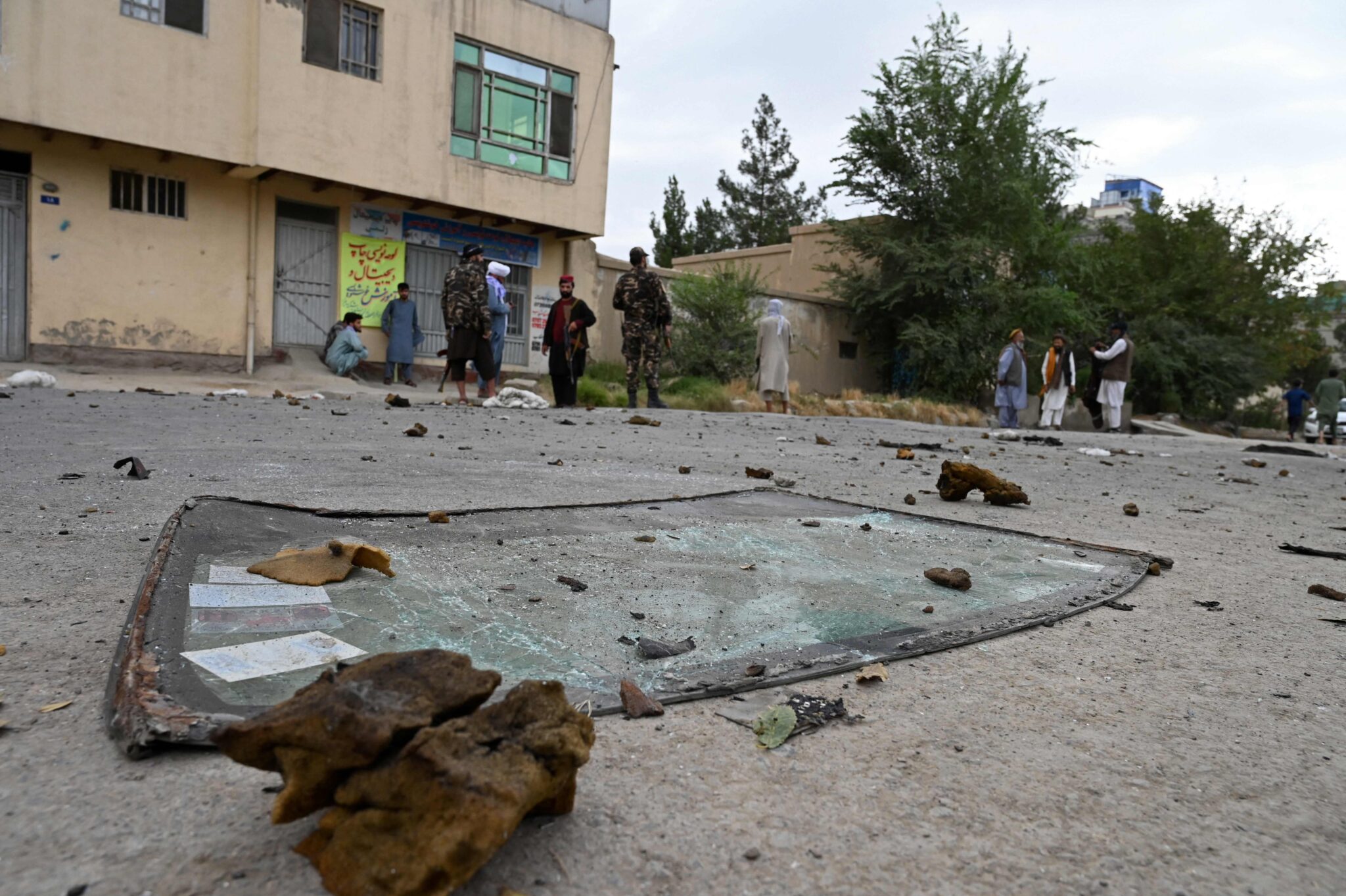 Taliban fighters stand guard near a damaged car (not pictured) after multiple rockets were fired in Kabul on August 30, 2021. Rockets flew across the Afghan capital on August 30 as the US raced to complete its withdrawal from Afghanistan, with the evacuation of civilians all but over and terror attack fears high. (Photo by WAKIL KOHSAR / AFP)