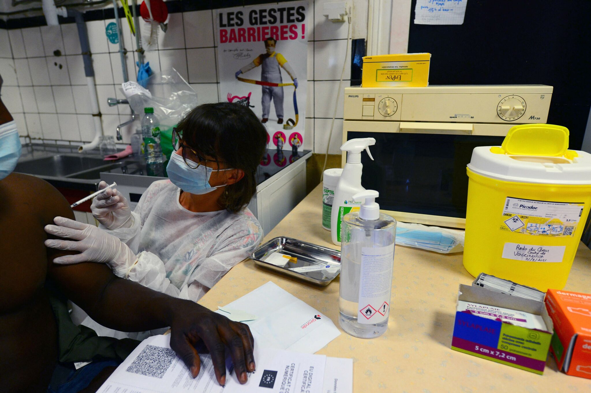 A patient receives a dose of Pfizer/BioNTech vaccine against the Covid-19, at the 'Restos du Coeur' place, in Bordeaux, southern France, on August 31, 2021. (Photo by MEHDI FEDOUACH / AFP)