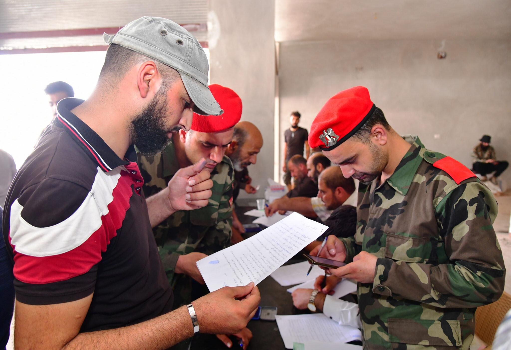 (210901) -- DARAA (SYRIA), Sept. 1, 2021 (Xinhua) -- Armed men settle their criminal records with Syrian military police in Daraa province, southern Syria, on Sept. 1, 2021. A new deal to defuse the tension in Daraa province went into force on Wednesday, starting with a number of armed rebels surrendering to the Syrian authorities, according to state news agency SANA and a war monitor. (Photo by Ammar Safarjalani/Xinhua)