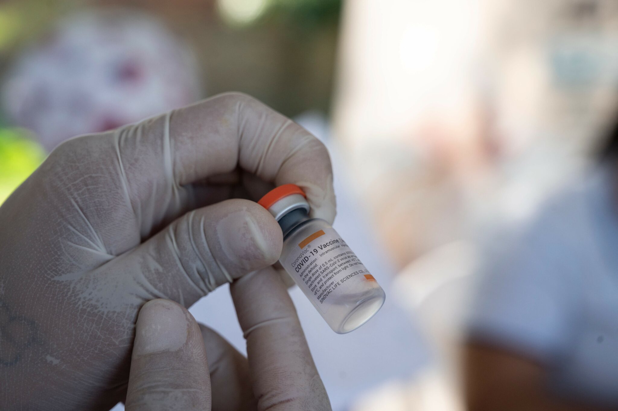 A Colombian health worker prepares a dose of the CoronaVac vaccine against COVID-19 to inoculate a Venezuelan child between 2 and 11 years old at the Francisco de Paula Santander International Bridge in the border city of Cucuta, Colombia on November 13, 2021. (Photo by Yuri CORTEZ / AFP)