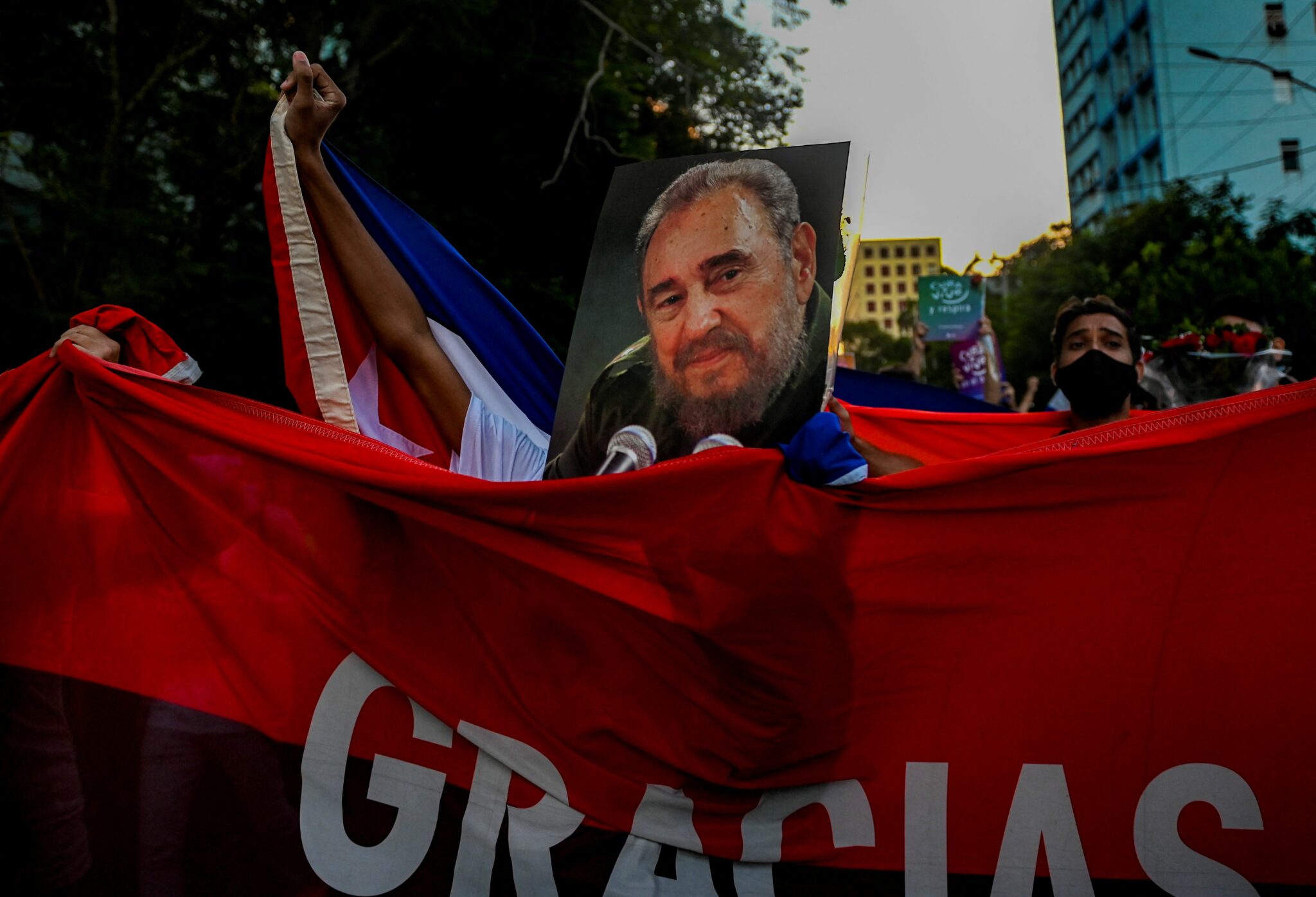 Young people walk with posters and Cuban flags along a Havana street during the 5th anniversary of Fidel Castro's physical disappearance, on November 25, 2021. Five years after Fidel Castro's death, the revolution he started in 1959 appears to be at an impasse, with Cuba's economy battered and an ever-larger part of its population clamoring for change. (Photo by YAMIL LAGE / AFP)