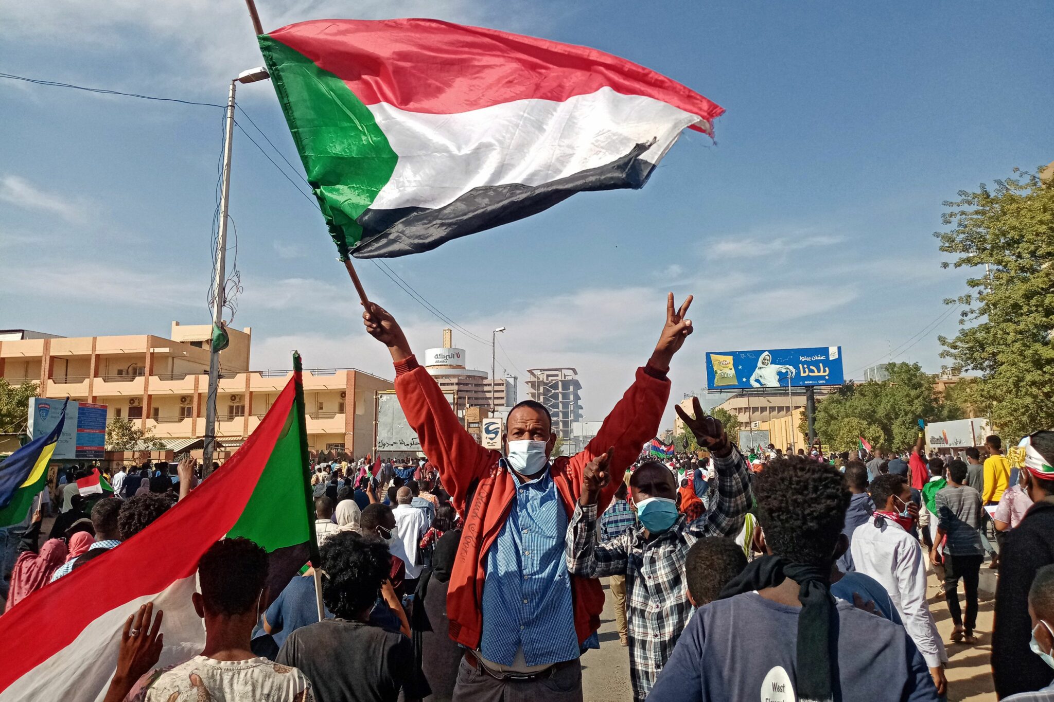 A Sudanese protester waves the national flag during a rally to mark three years since the start of mass demonstrations that led to the ouster of strongman Omar al-Bashir, in the capital Khartoum on December 19, 2021. Sudanese security forces fired tear gas at a huge crowd of protesters who had gathered near the republican palace in the capital Khartoum, witnesses told AFP. Tens of thousands rallied on Sunday to mark three years since the start of demonstrations that led to the ouster of strongman Omar al-Bashir, as well as against the current military chief, General Abdel Fattah al-Burhan. (Photo by AFP)