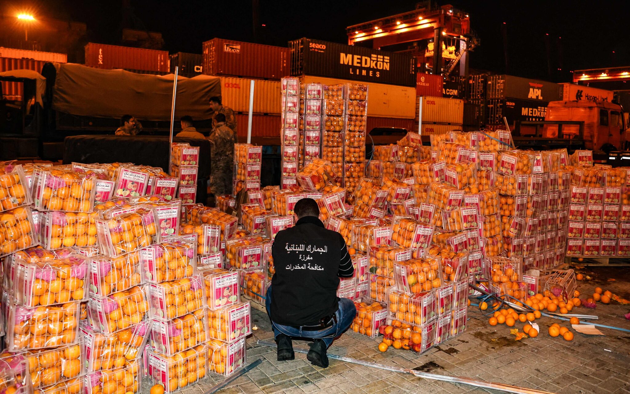 A customs agent checks boxes of oranges, in which fake fruits filled with Captagon pills were dissimulated among real fruit, after the shipment was intercepted by the customs and the anti-drug brigade at the Beirut port, in the Lebanese capital, on December 29, 2021. Lebanese customs agents seized today, nine million Captagon pills hidden in a shipment of oranges in the port of Beirut, destined to one of the Gulf countries, Lebanon's Interior Minister Bassan al-Mawlawi announced. (Photo by ANWAR AMRO / AFP)