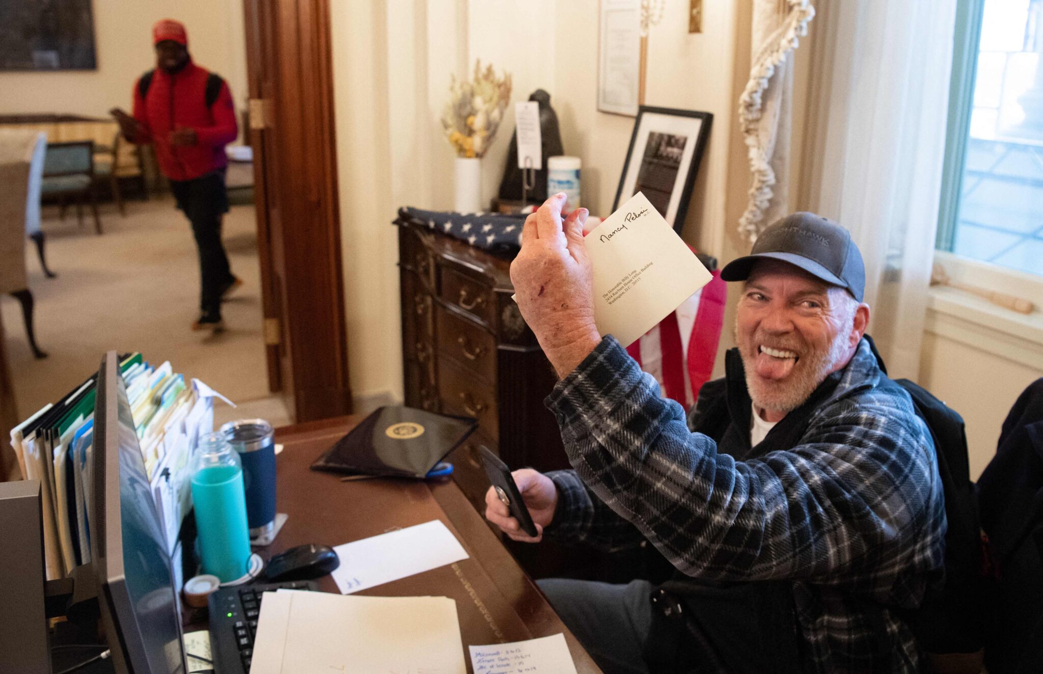 (FILES) In this file photo taken on January 06, 2021, Richard Barnett, a supporter of US President Donald Trump, holds a piece of mail as he sits inside the office of US Speaker of the House Nancy Pelosi after protestors breached the US Capitol in Washington, DC. They descended upon Washington, DC in the thousands, gathering to protest the result of a presidential election they still claim was "rigged." The US Capitol came under attack, leaving the country wounded. The world watched live, aghast, as the citadel of American democracy came under assault. During the next few months, two competing narratives would arise. Trump supporters claim it was a peaceful protest against a "stolen" election. Police officers who fought with the mob, Democratic lawmakers and even some Republicans called it "terrorism." (Photo by SAUL LOEB / AFP)