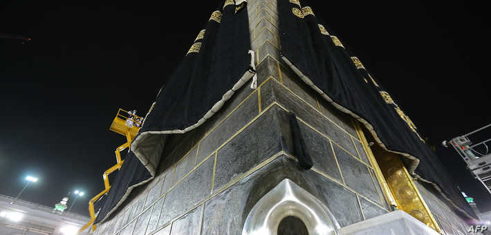 This picture taken on July 19, 2021 on the night before the start of the annual hajj pilgrimage, shows a view of the Hajar al-Aswad or the "Black Stone", a rock set to the eastern corner of the Kaaba believed by Islamic tradition to date to the time of Adam and Eve, as labourers put on the new Kiswa, the protective cover that engulfs the shrine, made from black silk and gold thread and embroidered with Koran verses, in Saudi Arabia's holy city of Mecca. - The drape which engulfs the Kaaba is formally called Kiswa and is changed every year at the culmination of the annual hajj, or pilgrimage, when the pilgrims have left Mecca to go to Arafat, the starting point of their hajj journey. (Photo by AFP)