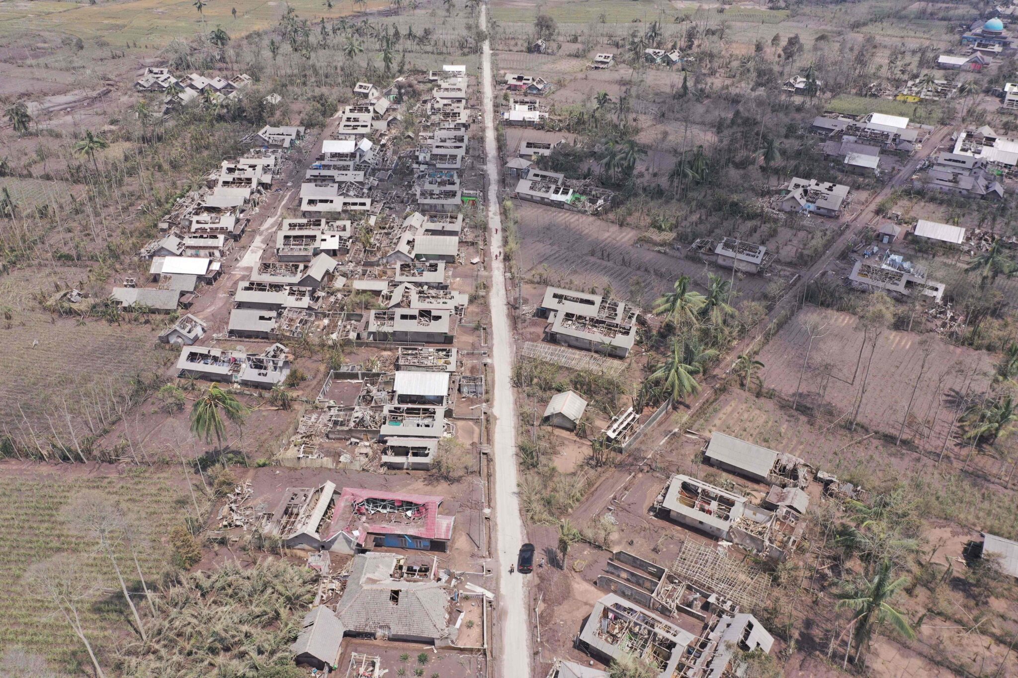 TOPSHOT - This aerial photo shows houses and farms covered in ash following the eruption of Mount Semeru volcano, in Curah Kobokan village in Lumajang on December 8, 2021. (Photo by ADEK BERRY / AFP)