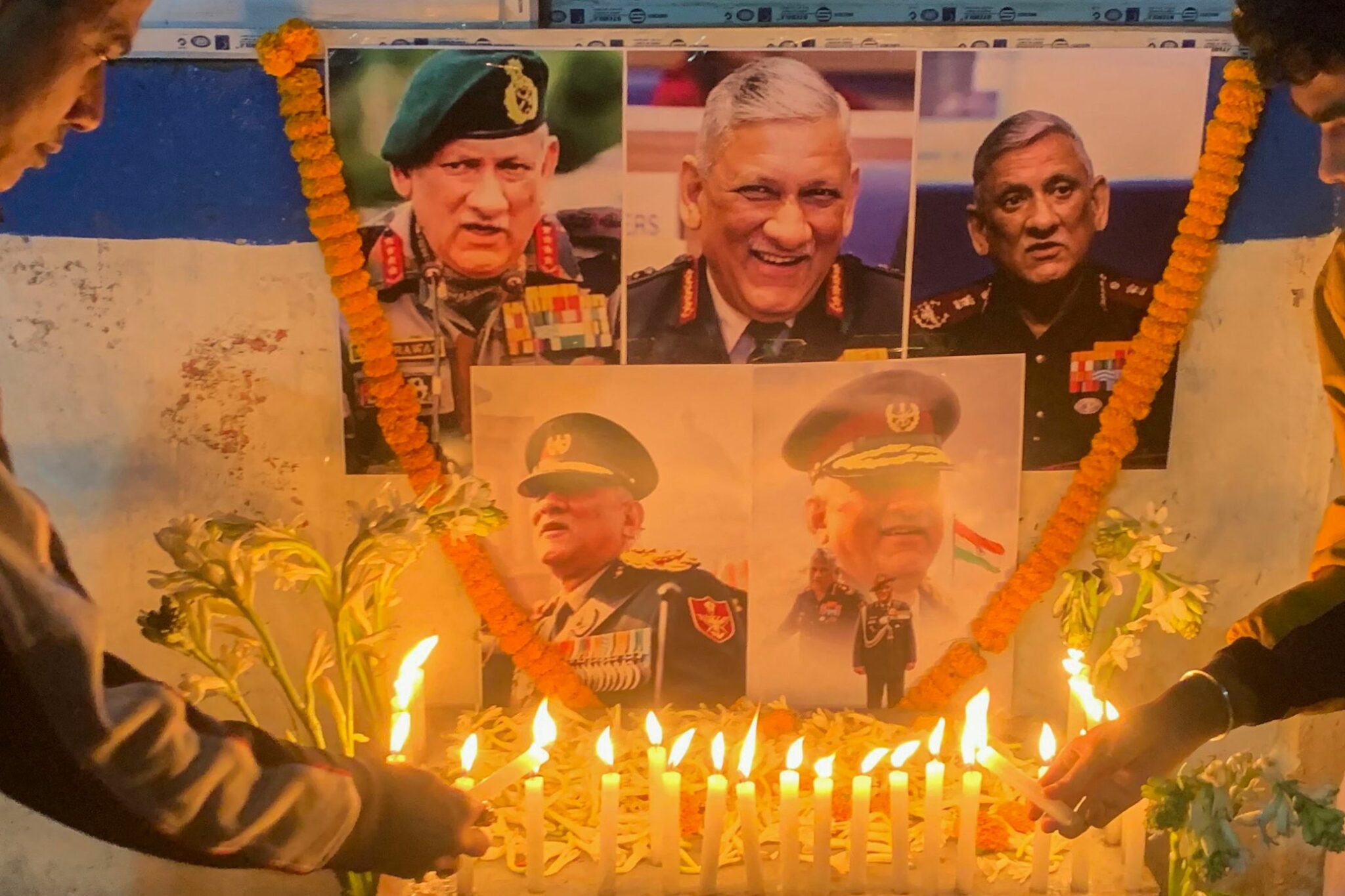 People light candles to pay their respect in front of a portrait of defence chief General Bipin Rawat in Siliguri on December 8, 2021 after reports of a helicopter crash in which defence chief General Bipin Rawat and his wife were among 13 casualties. (Photo by Diptendu DUTTA / AFP)