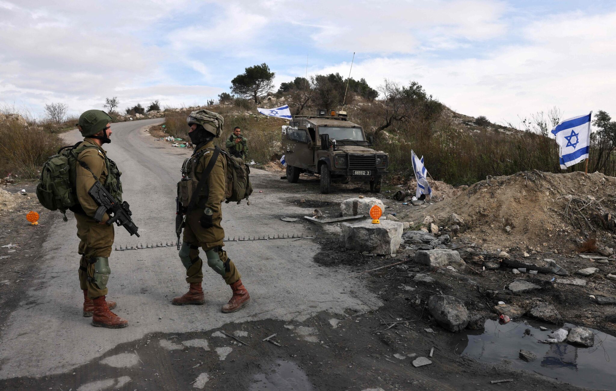 Israeli soldiers guard the road leading to the Homesh Yeshiva (religious school), located at the former settlement of Homesh, west of the West Bank city of Nablus, on December 30, 2021. The Homesh settlement was demolished in 2005 as part of the Israeli disengagement from Gaza, along with a few other settlements in the north of the West Bank. (Photo by MENAHEM KAHANA / AFP)