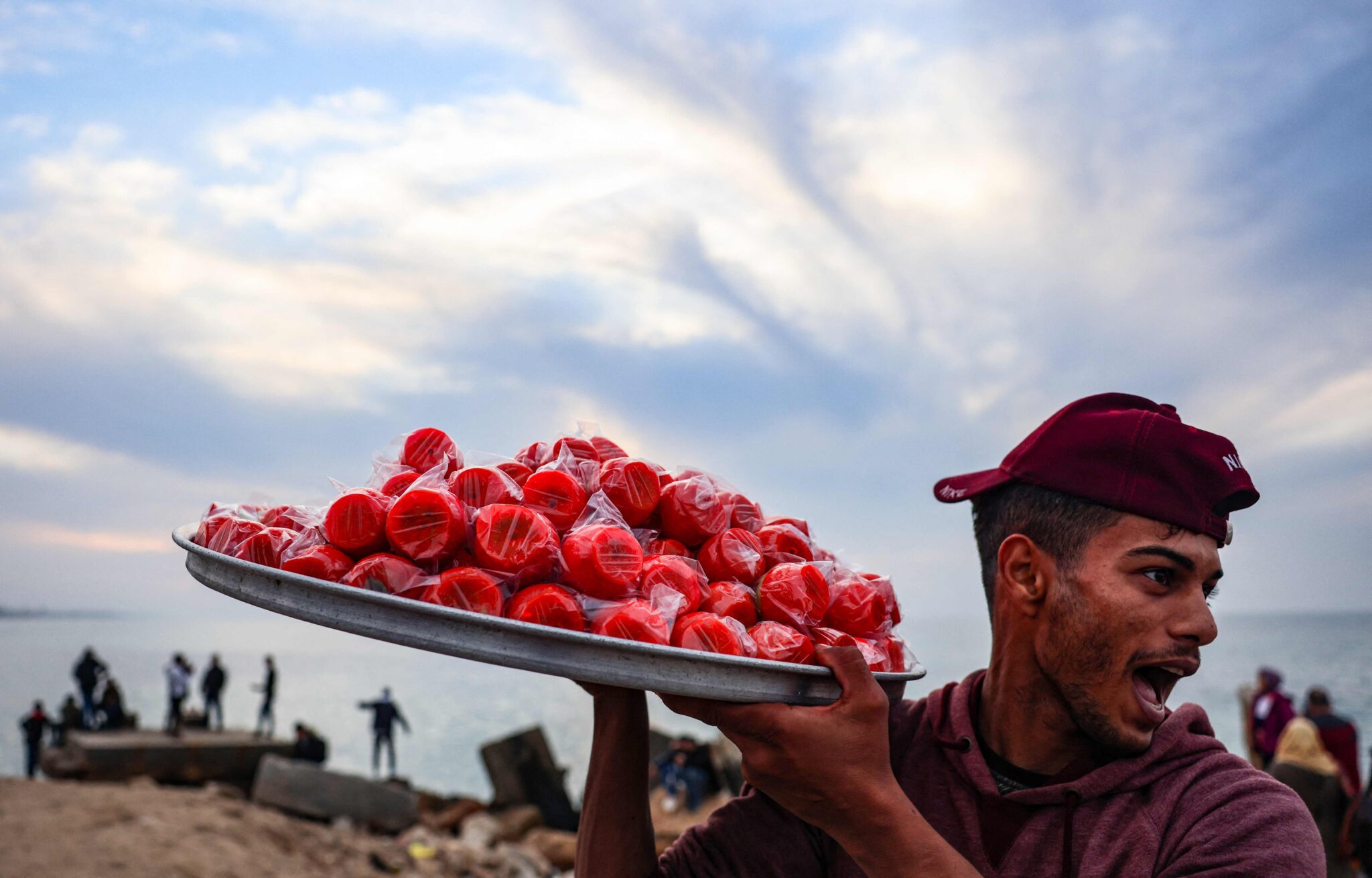 A Palestinian vendor yells to attract customers as he sells sugar-coated apples along the beach in Gaza city, on January 6, 2022. (Photo by MOHAMMED ABED / AFP)