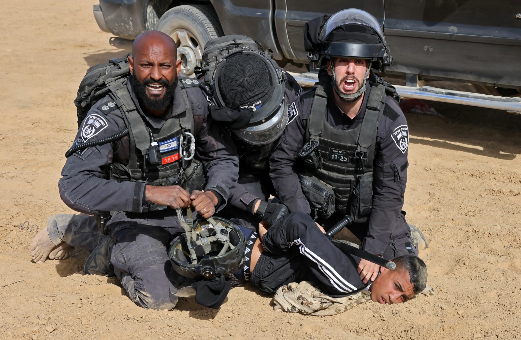 Israeli police detain a man as Bedouins protest in the southern Israeli village of Sawe al-Atrash in the Neguev Desert against an afforestation project by the Jewish National Fund (JNF), on January 12, 2022. Israel's government today sought to ease tensions with Bedouins over a controversial tree-planting project in the Negev desert, following days of unrest that marked the latest test for the fragile coalition (Photo by AHMAD GHARABLI / AFP)