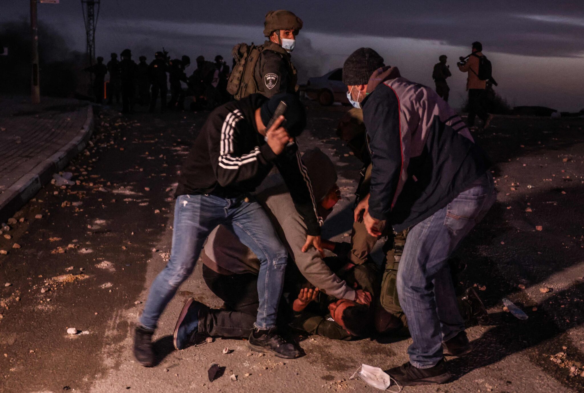 Israeli security forces arrest a young Beduin demonstrator during a protest in the southern Israeli village of Sawe al-Atrash in the Neguev Desert against an afforestation project by the Jewish National Fund (JNF), on January 13, 2022. Bedouin, who are part of Israel's 20 percent Arab minority, have long opposed tree-planting initiatives in the Negev, blasting them as a de facto government land grab in areas they call home. (Photo by Menahem KAHANA / AFP)