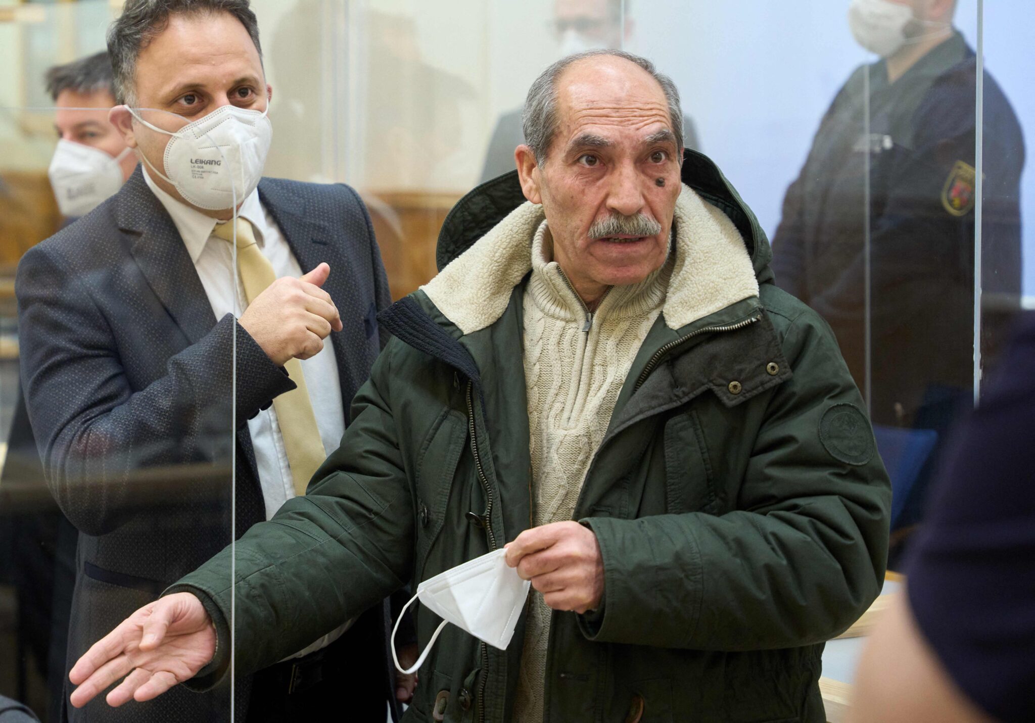 The defendant, former Syrian intelligence officer Anwar Raslan (R), gestures next to one of his lawyers in the courtroom at a courthouse in Koblenz, western Germany, on January 13, 2022 on the last day of his trial where he was sentenced to life in jail for crimes against humanity in the first global trial over state-sponsored torture in Syria. Anwar Raslan, 58, was found guilty of overseeing the murder of 27 people at the Al-Khatib detention centre in Damascus, also known as "Branch 251", in 2011 and 2012. - REPETITION OF NON-PIXELATED VERSION AFTER CONVICTION (Photo by Thomas Frey / POOL / AFP) / REPETITION OF NON-PIXELATED VERSION AFTER CONVICTION