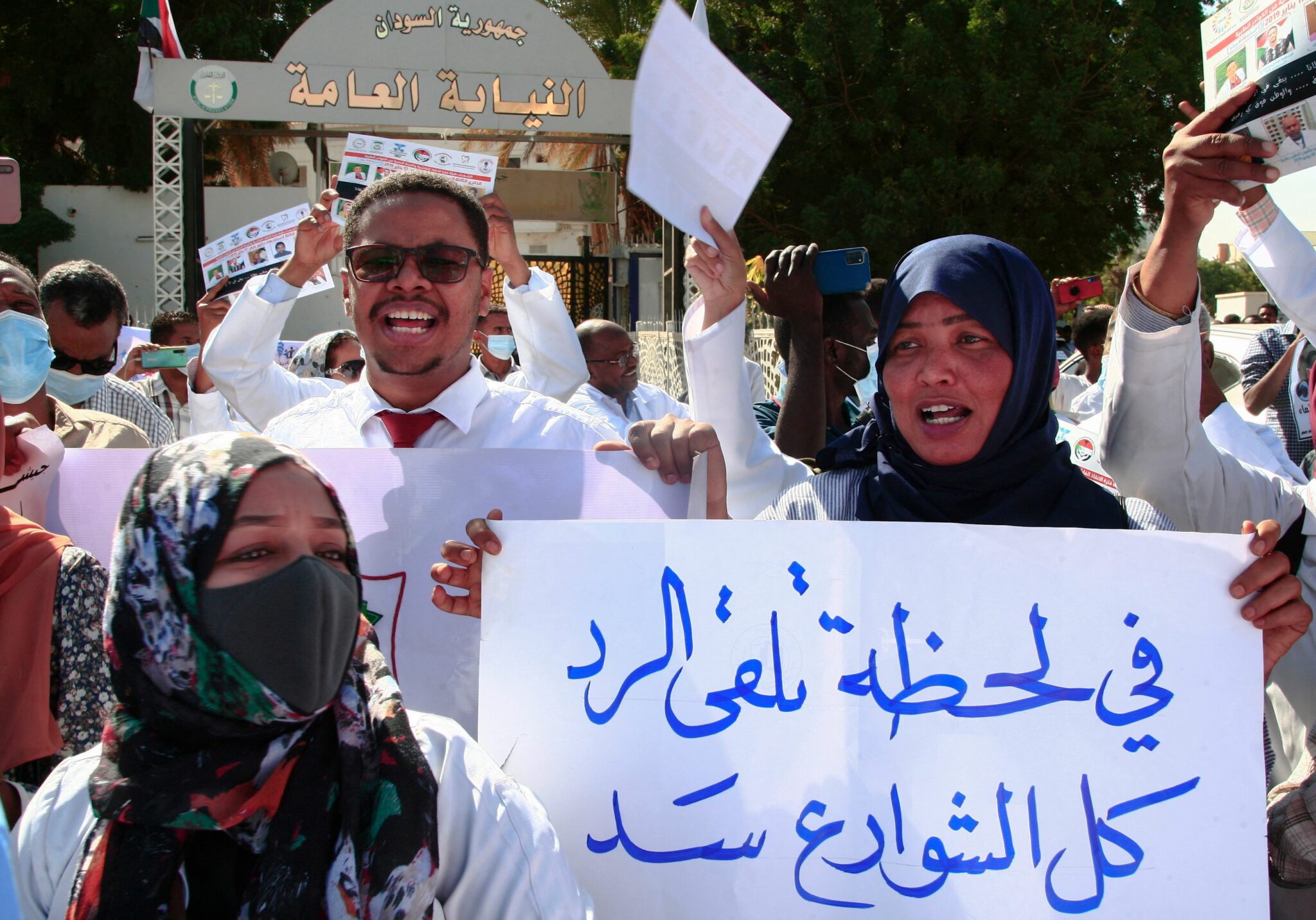 Dozens of Sudanese doctors demonstrate in Khartoum on January 16, 2022 to denounce attacks by security forces against medical personnel and doctors during pro-democracy rallies opposed to the October military coup. Arabic writing on placard reads "our promt answer is blocking the roads". Carrying pictures of colleagues they say have been killed in the turmoil that has gripped Sudan over the past months, the doctors rallied dressed in their white uniforms. According to the World Health Organization (WHO) there have been 11 confirmed attacks on health workers and health facilities in Sudan since November. (Photo by AFP)