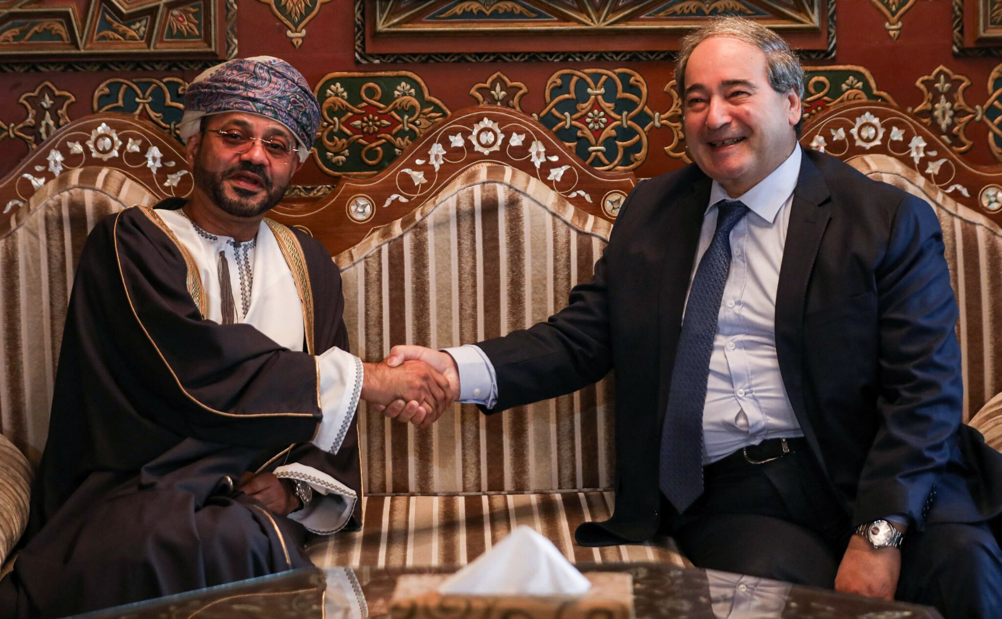 (R to L) Syria's Foreign Minister Faisal Mekdad shakes hands with his Omani counterpart Sayyid Badr al-Busaidi during a reception for the latter in the capital Damascus on January 31, 2022. (Photo by Louai Beshara / AFP)