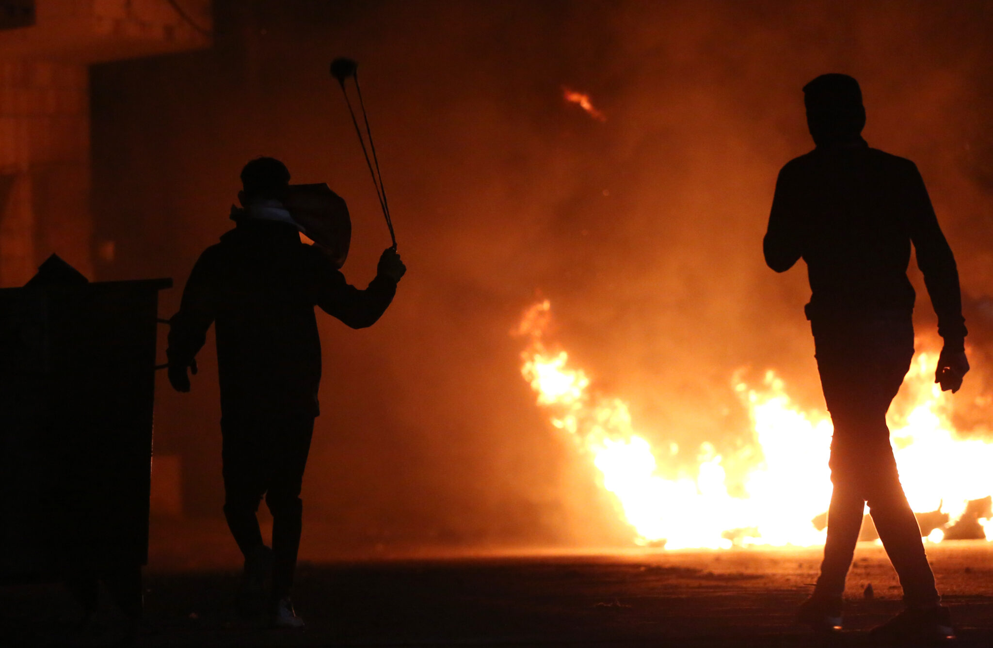 (220113) -- NABLUS, Jan. 13, 2022 (Xinhua) -- A Palestinian protester uses a slingshot to hurl a stone at Israeli soldiers during clashes in the village of Burqa near the West Bank city of Nablus, on Jan. 13, 2022. (Photo by Ayman Nobani/Xinhua)