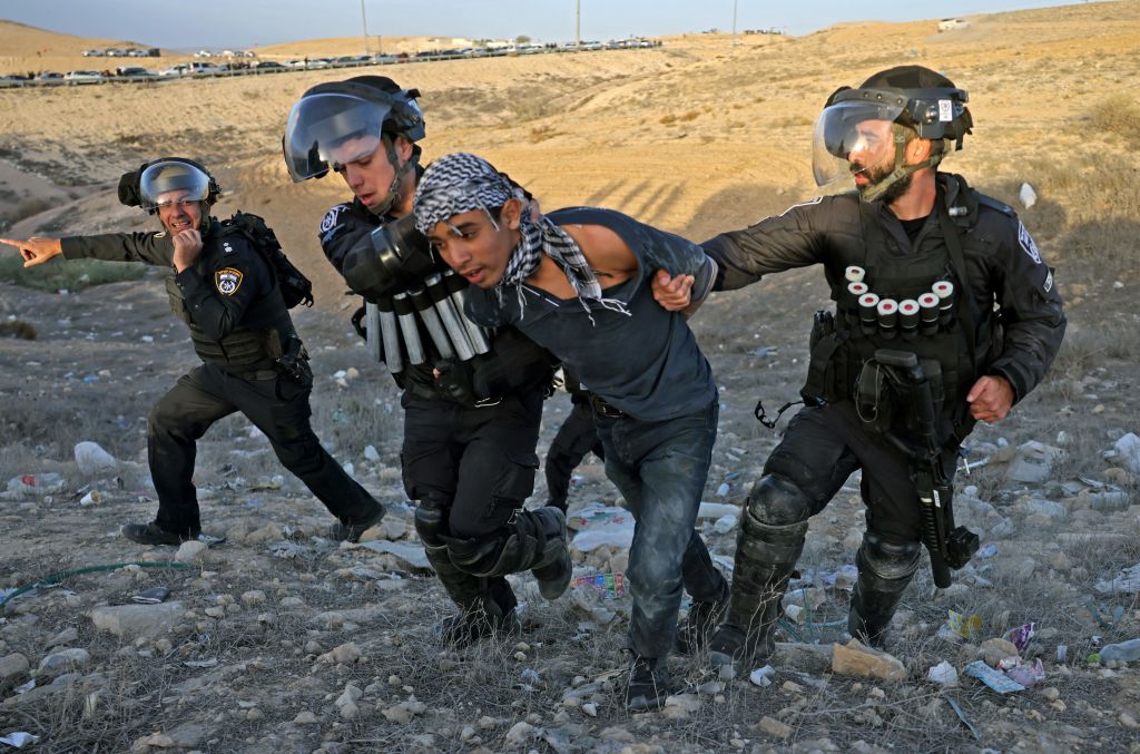 Israeli security forces arrest a young Beduin demonstrator during a protest in the southern Israeli village of Sawe al-Atrash in the Neguev Desert against an afforestation project by the Jewish National Fund (JNF), on January 13, 2022. - Bedouin, who are part of Israel's 20 percent Arab minority, have long opposed tree-planting initiatives in the Negev, blasting them as a de facto government land grab in areas they call home. (Photo by Menahem KAHANA / AFP) (Photo by MENAHEM KAHANA/AFP via Getty Images)