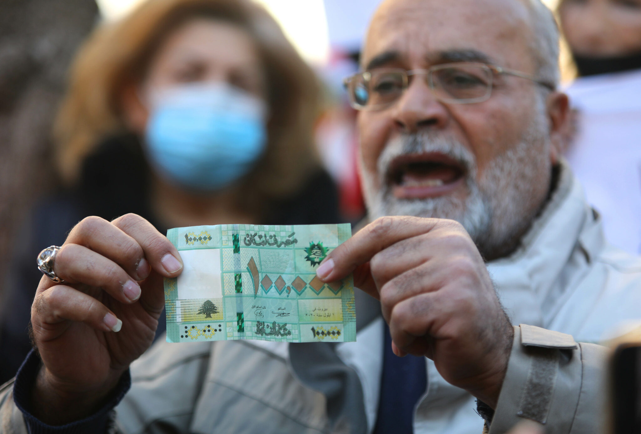 (220109) -- BEIRUT, Jan. 9, 2022 (Xinhua) -- A man displays a banknote of 100,000 Lebanese pounds during a protest against the collapse of the national currency in front of the Central Bank "Banque du Liban" in Beirut, Lebanon, Jan. 8, 2022. (Xinhua/Bilal Jawich)