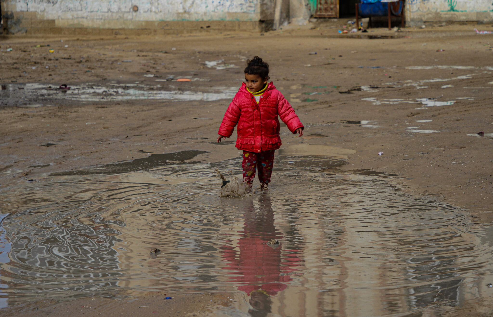 (220125) -- GAZA CITY, Jan. 25, 2022 (Xinhua) -- A Palestinian girl plays outside in cold weather at Al-Shati refugee camp in Gaza City, on Jan. 24, 2022. (Photo by Rizek Abdeljawad/Xinhua)