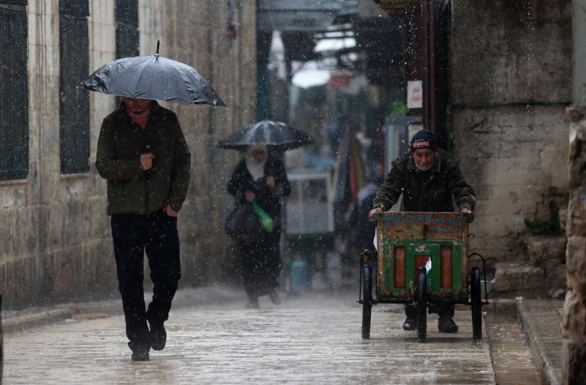 (211221) -- NABLUS, Dec. 21, 2021 (Xinhua) -- Palestinians walk on a street in the rain in the West Bank City of Nablus, on Dec. 21, 2021. (Photo by Nidal Eshtayeh/Xinhua)