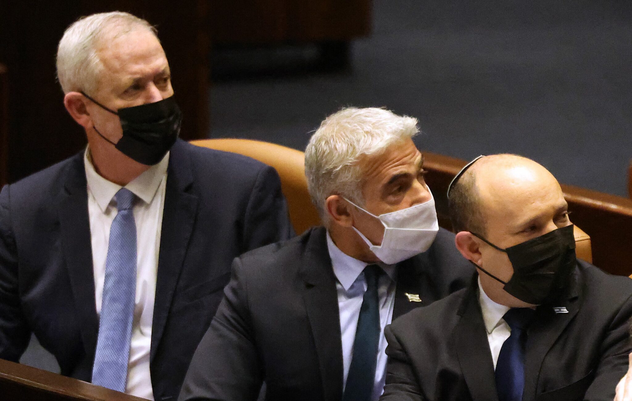 (L to R) Israeli Defence Minister Benny Gantz, Foreign Minister Yair Lapid, Prime Minister Naftali Bennett, attend a plenum session in the presence of the speaker of the United States House of Representatives in, in the Knesset (Israeli parliament), in Jerusalem on February 16, 2022. (Photo by Menahem KAHANA / AFP)