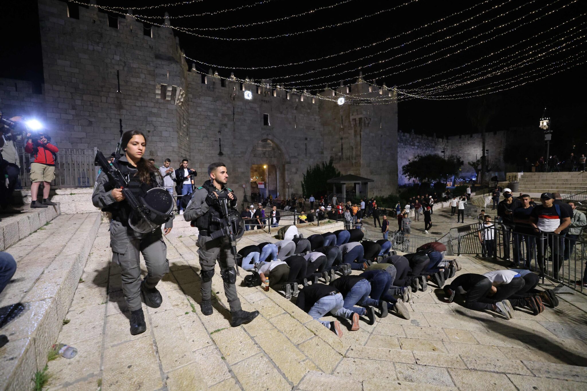 Israeli security forces patrol as Palestinians perform prayers outside the Damascus Gate in Jerusalem's Old City on April 24, 2021, after several nights of unrest. / AFP / EMMANUEL DUNAND