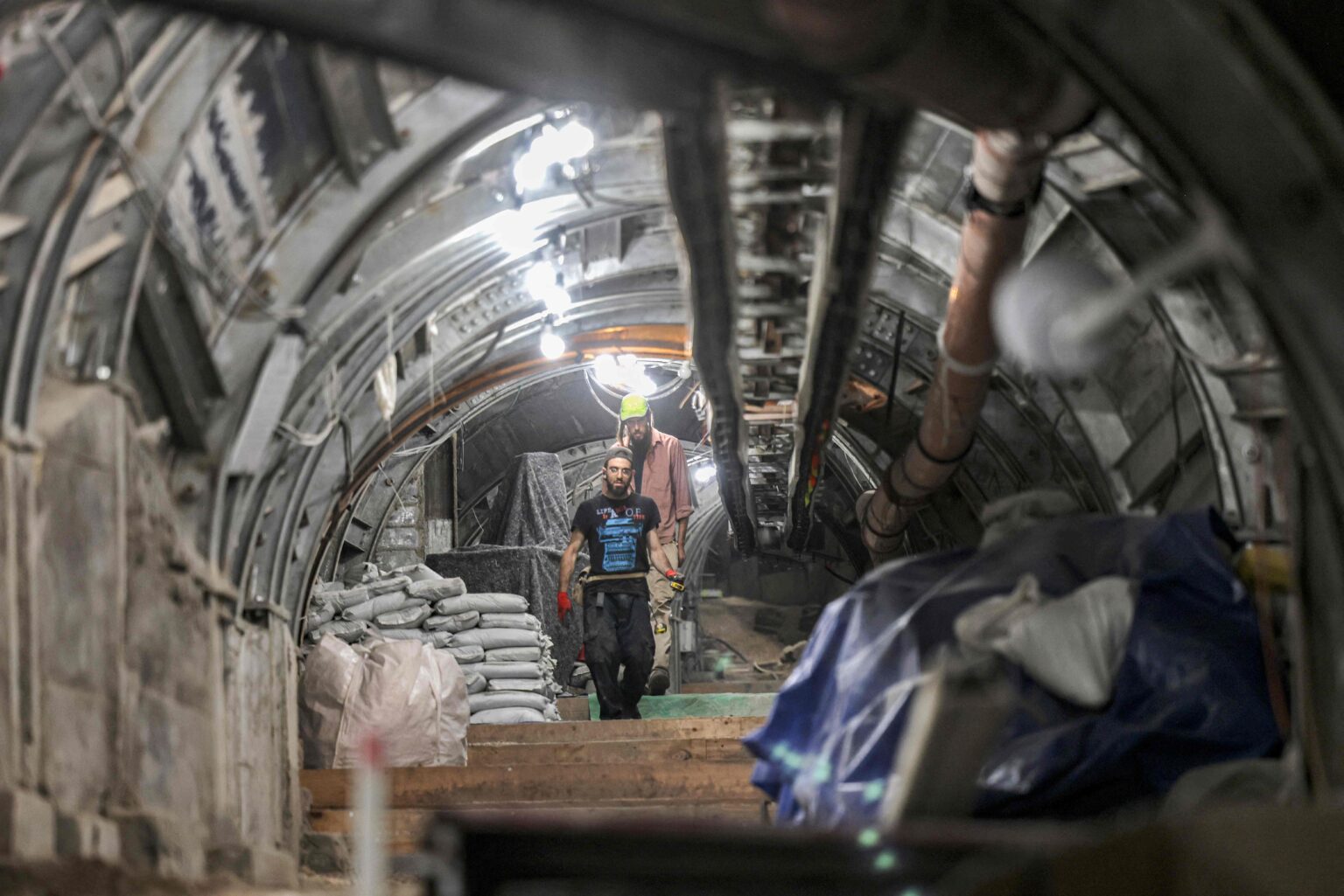 Workers for the Israel Antiquities Authority walk in an underground tunnel during excavations of the City of David's Pilgrimage Road outside the old city of Jerusalem on May 5, 2021. Archaeologists say this special bronze lamp was deliberately buried in the foundations of the building, dating to the Roman Period, subsequent to the destruction of Jerusalem and the Second Temple in 70 CE (late 1st-early 2nd century CE) as a foundation deposit "to ensure the continued existence of the building and its occupants". / AFP / MENAHEM KAHANA