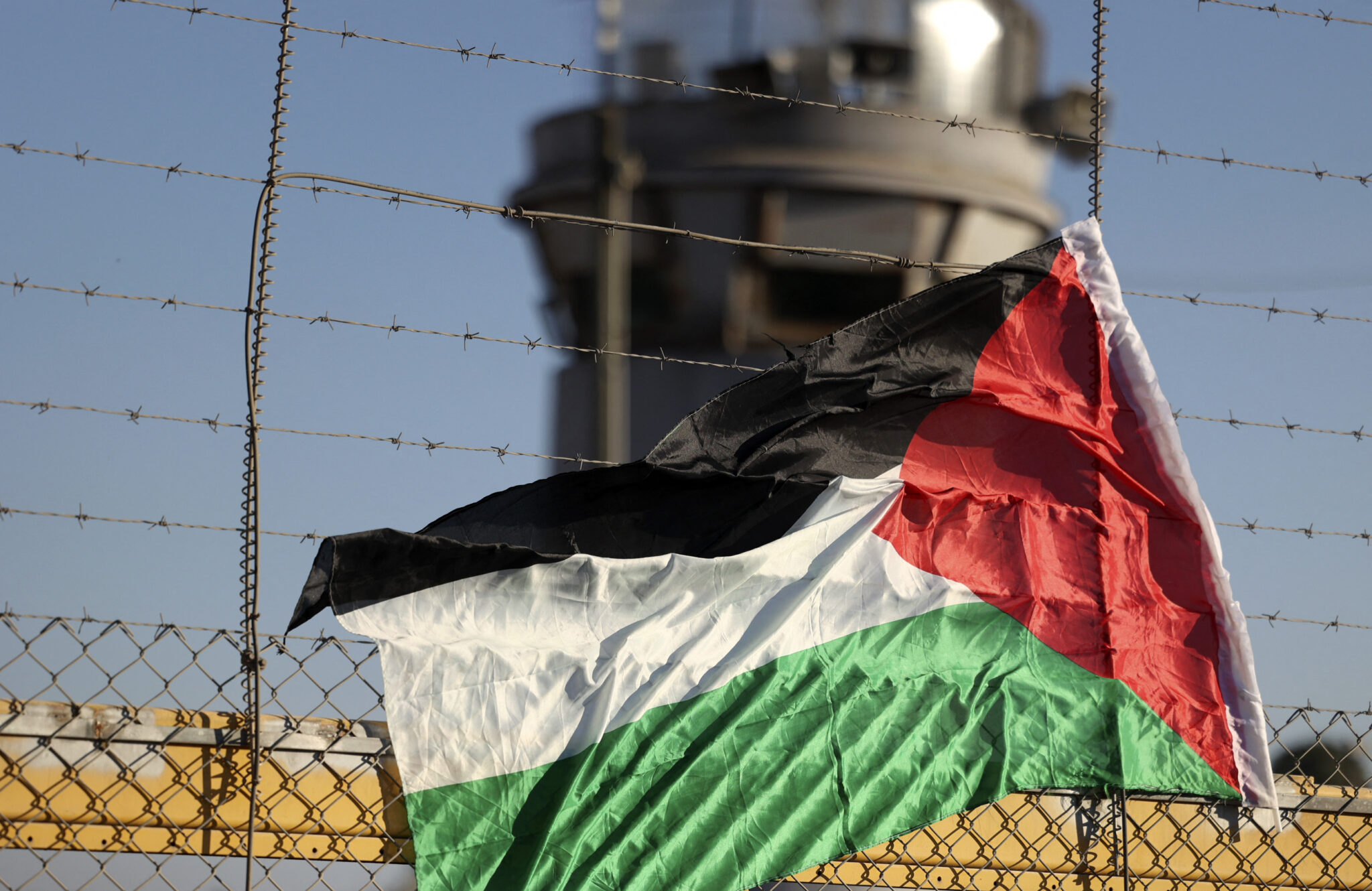 A Palestinian flag is pictured on the fence of Israel's Ofer prison near the city of Ramallah in the occupied West Bank, on July 12, 2021, during a protest by Palestinians demanding the release of the detainee Khaleda Jarrar after the death of her daughter in the city of Ramallah last night. / AFP / ABBAS MOMANI