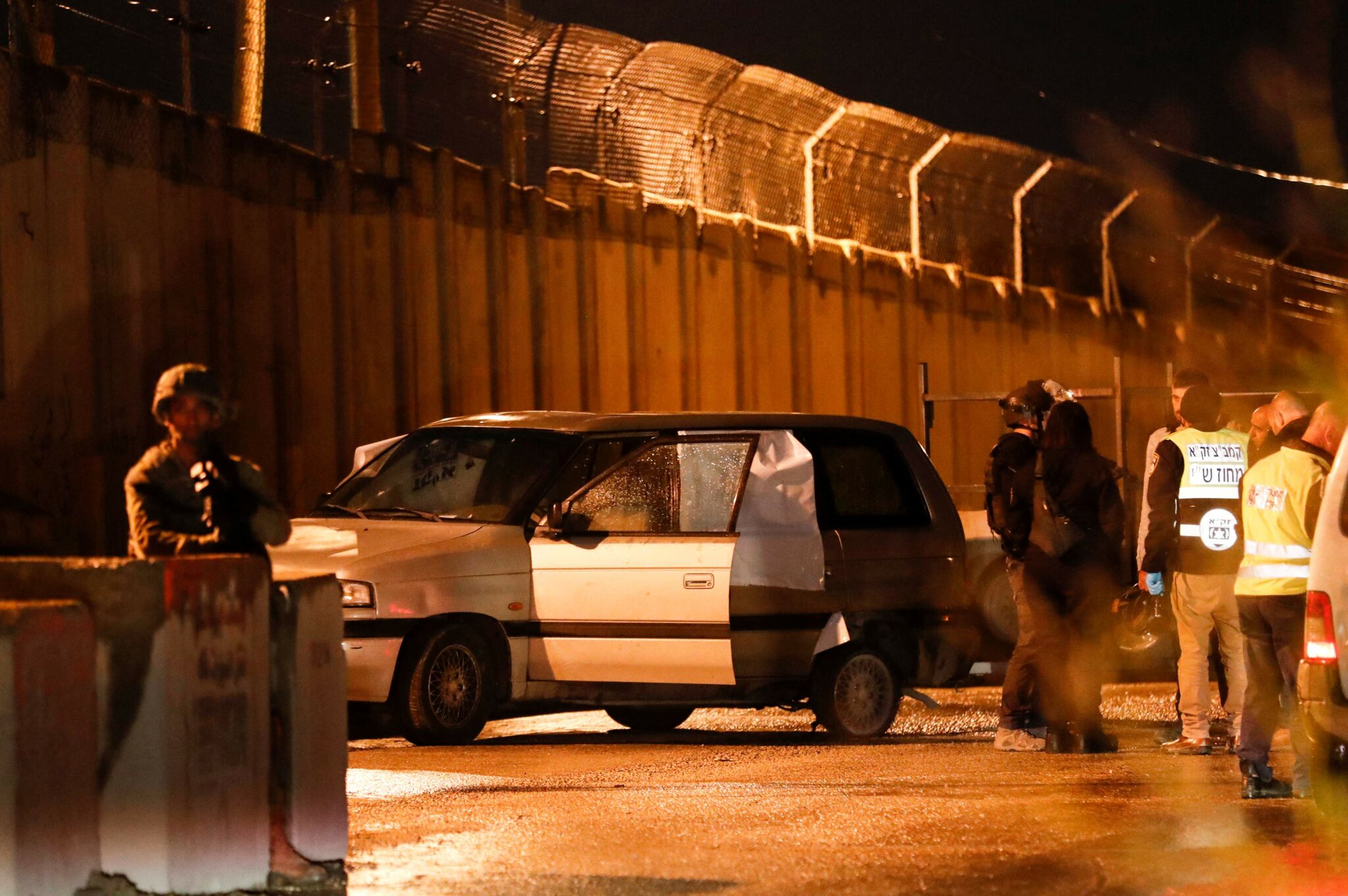 Members of the Israeli security forces and forensic experts inspect the car in which three Israelis came under gunfire, near a settlement in the ocuupied West Bank, on December 16, 2021. An Israeli religious student was killed and two wounded when their car came under gunfire near a settlement in the Israeli-occupied West Bank. (Photo by Ahmad GHARABLI / AFP)