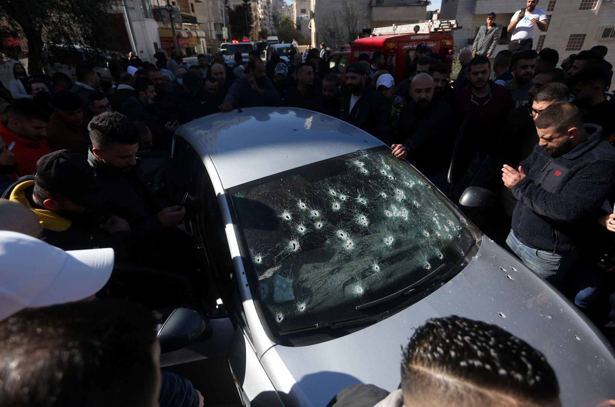 (220208) -- NABLUS, Feb. 8, 2022 (Xinhua) -- People gather around a car belonging to three Palestinians killed by Israeli soldiers, in the West Bank city of Nablus, on Feb. 8, 2022. Israel confirmed on Tuesday its forces killed three Palestinians in the Israeli-occupied West Bank during an alleged "operation to thwart a terror cell." (Photo by Ayman Nobani/Xinhua)